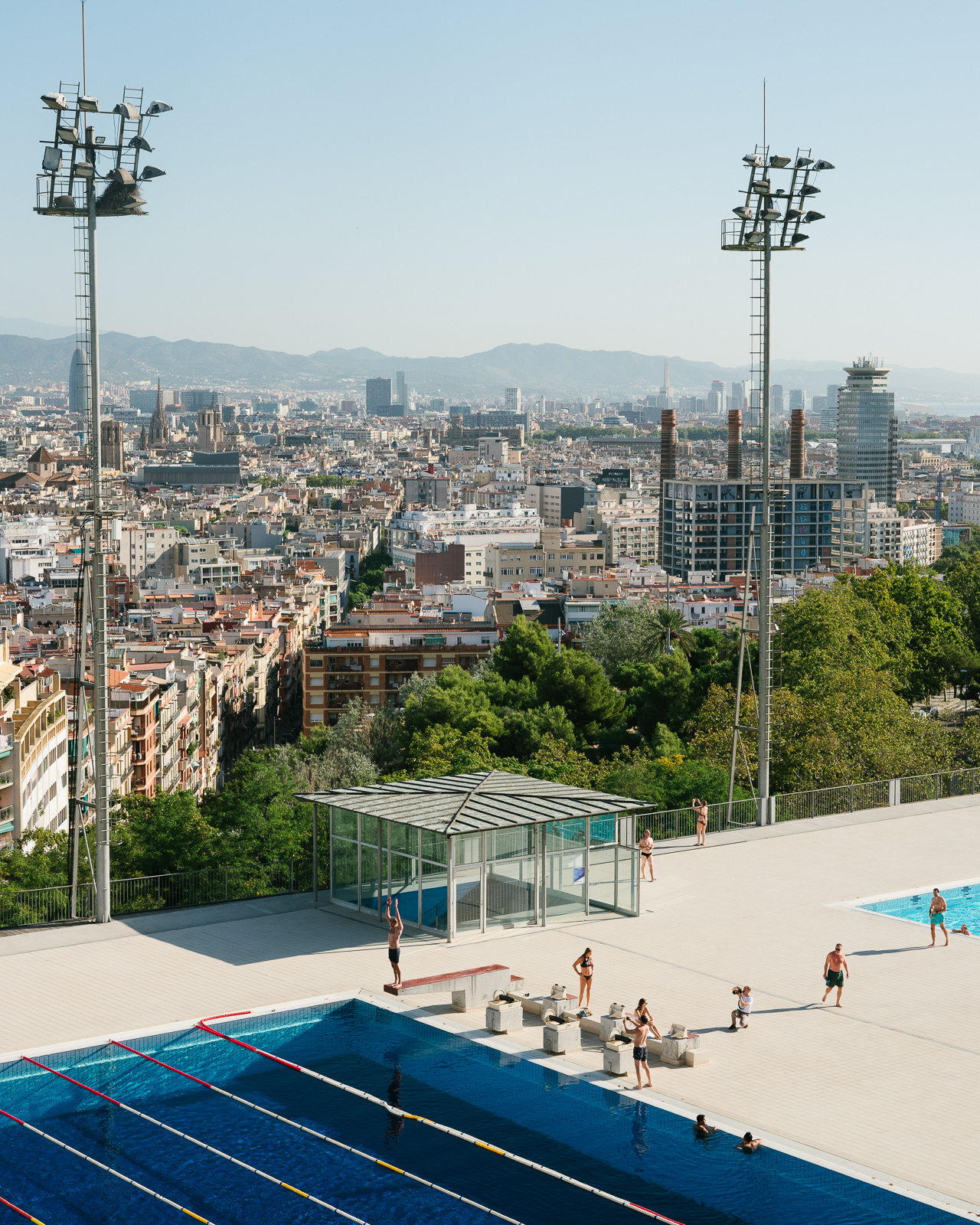 Piscina Municipal de Montjuïc in Barcelona, Spain, where several people are enjoying a sunny day.