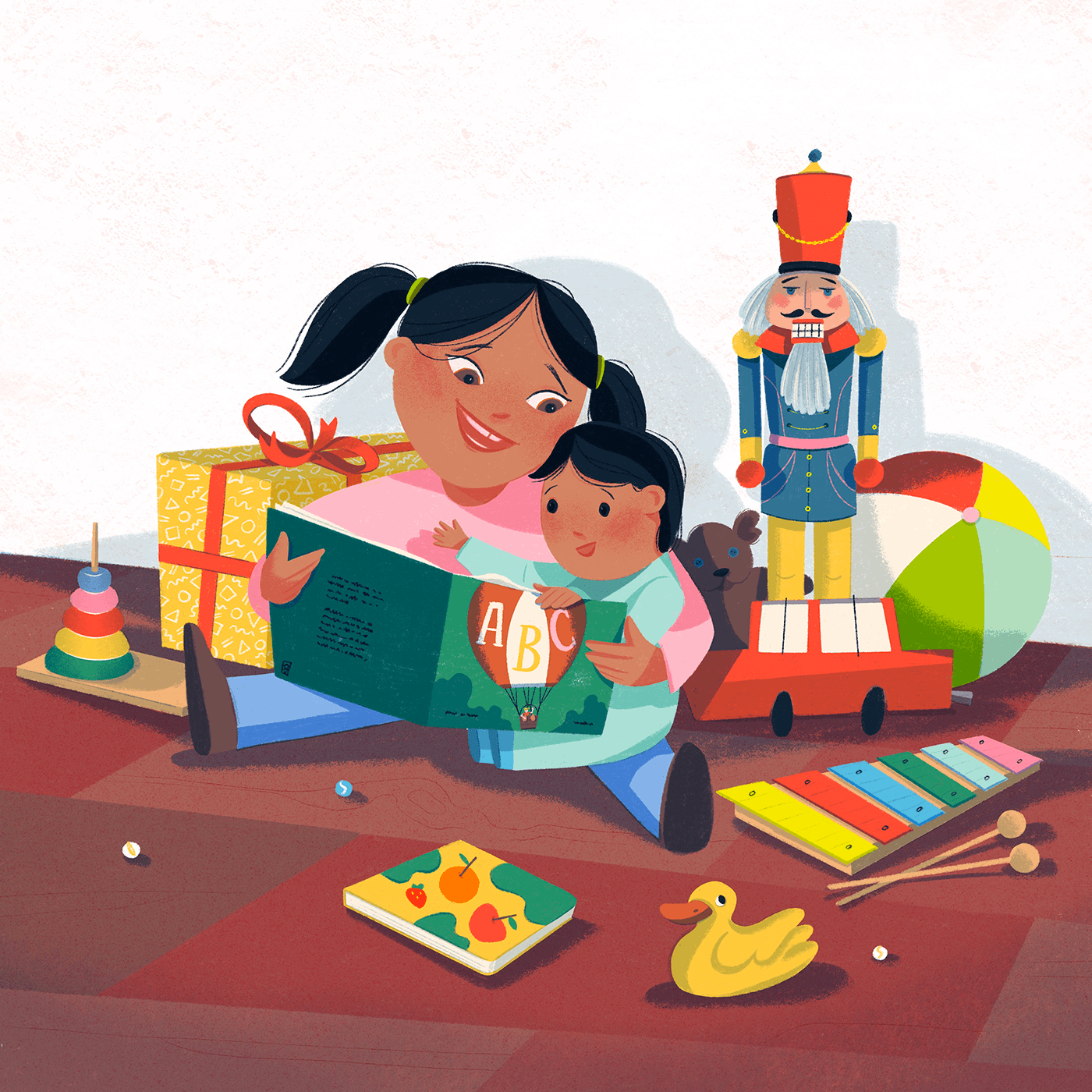 A girl reads a book to a little boy, their are sitting on the wooden floor, surrounded by toys.