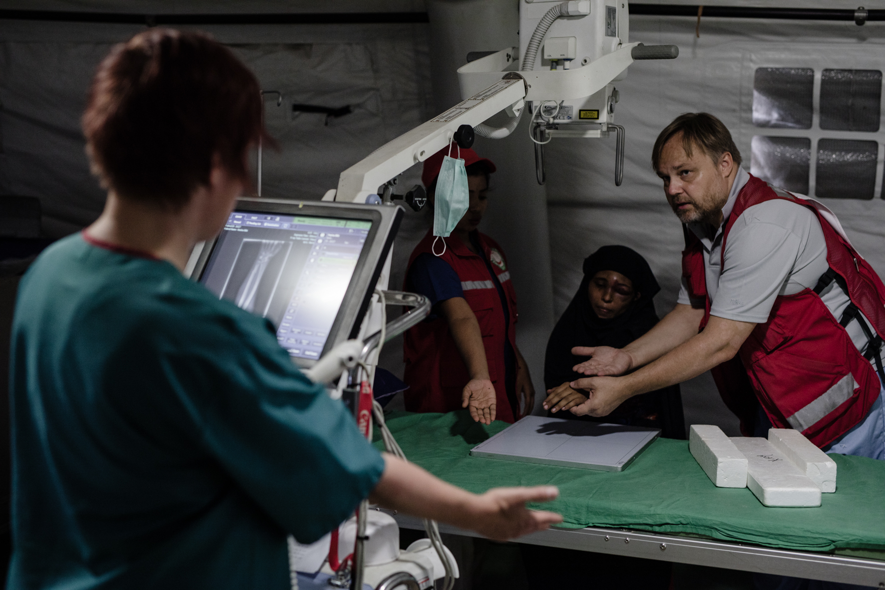 X-ray technician Miia Eklund, nurse Labani Barai and doctor Kimmo Maaranniitty discussing what would be the best way to take an x-ray of Hasina's fractured hand.