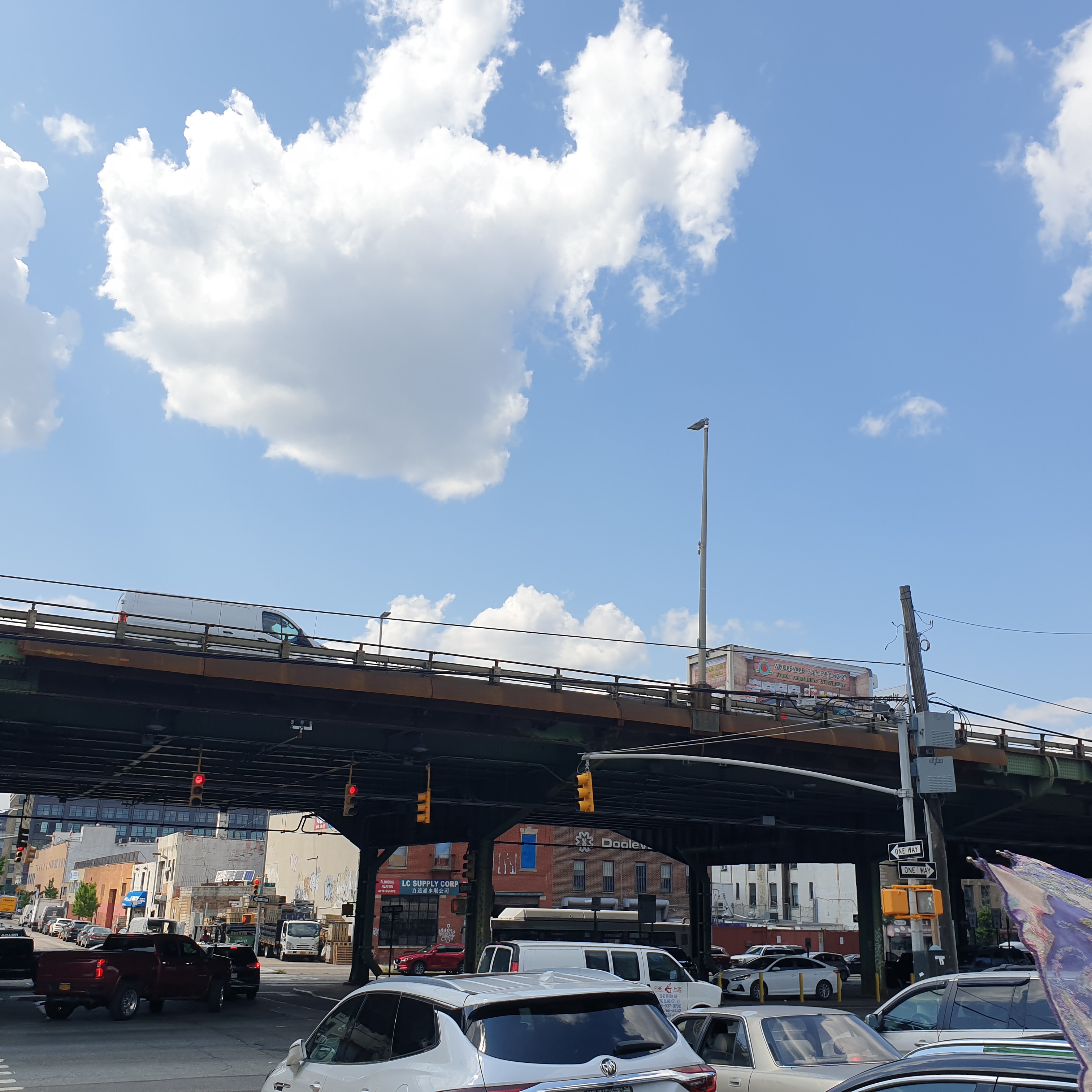 The Brooklyn Queens Expressway is visible in the background with cars and trucks driving on it as well as below it.