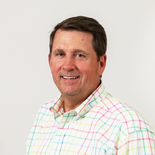 Headshot of Mark Falkner. He is wearing a multi-colored plaid button down shirt.
