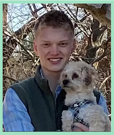 Tutor and his dog pose for a portrait in the woods