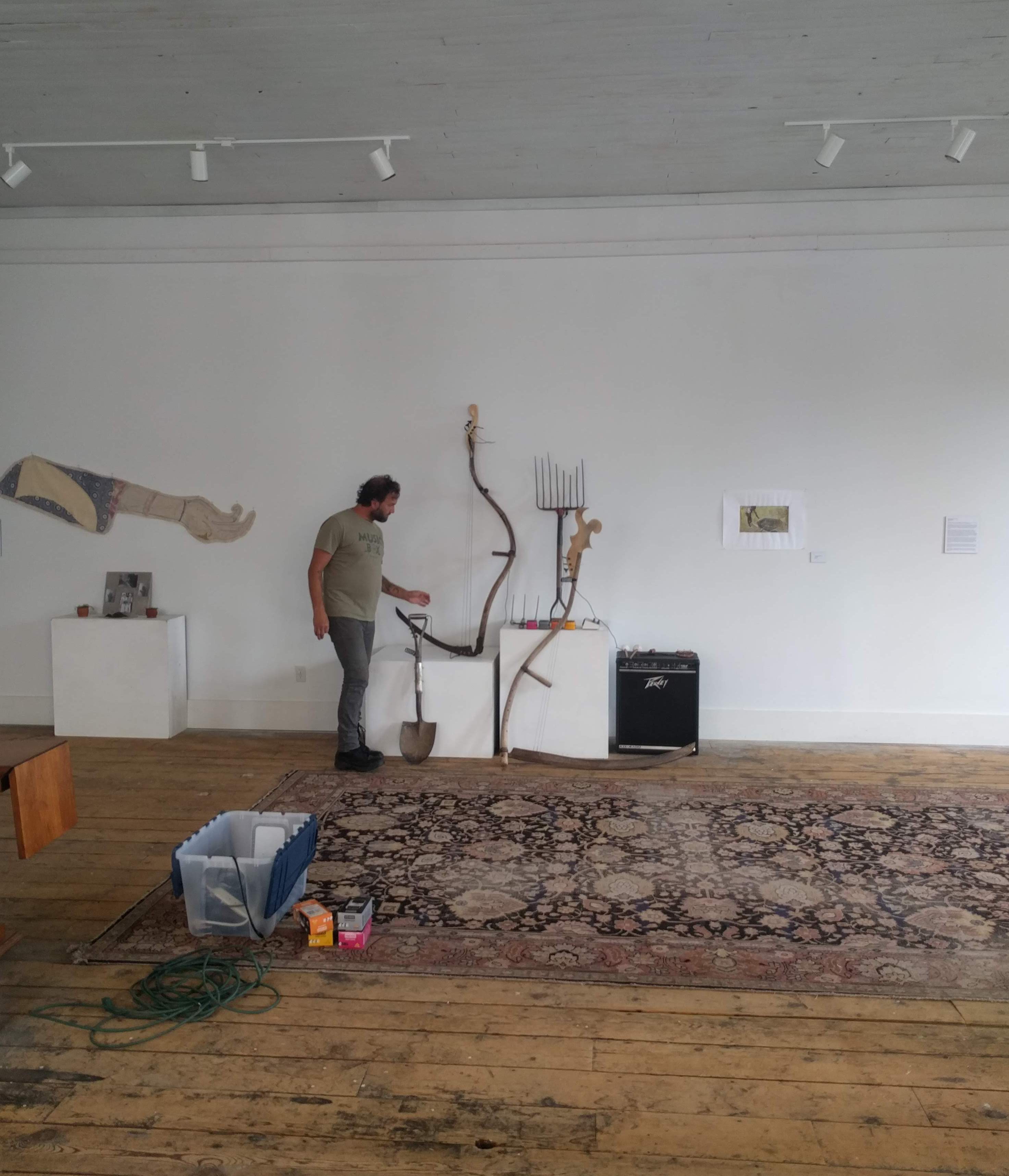 (From left) Jhani Randhawa's altar and Tory Tepp inspecting his Earthtones instruments installed in Woolen Mill Gallery. Reedsburg, Wisconsin, 2019.