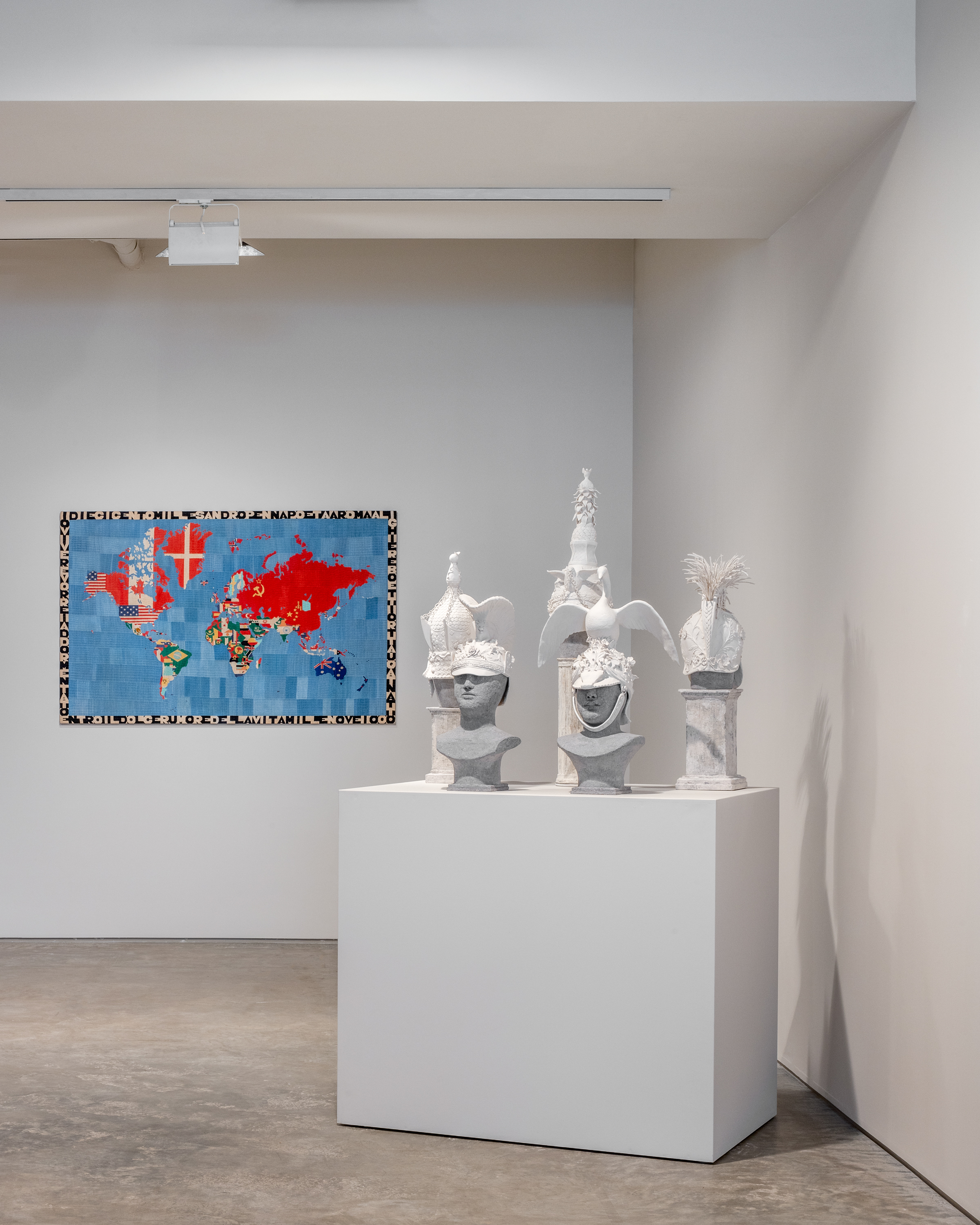 Left: Alighiero Boetti, &ldquo;Mappa&rdquo;, 1984, Embroidery on fabric, 44 3/8 x 70 1/8 inches. Right: Susan Hamburger, &ldquo;Helmet I-V&rdquo;, 2022, White paper clay, Dimensions variable. Image by Rafael Gamo.