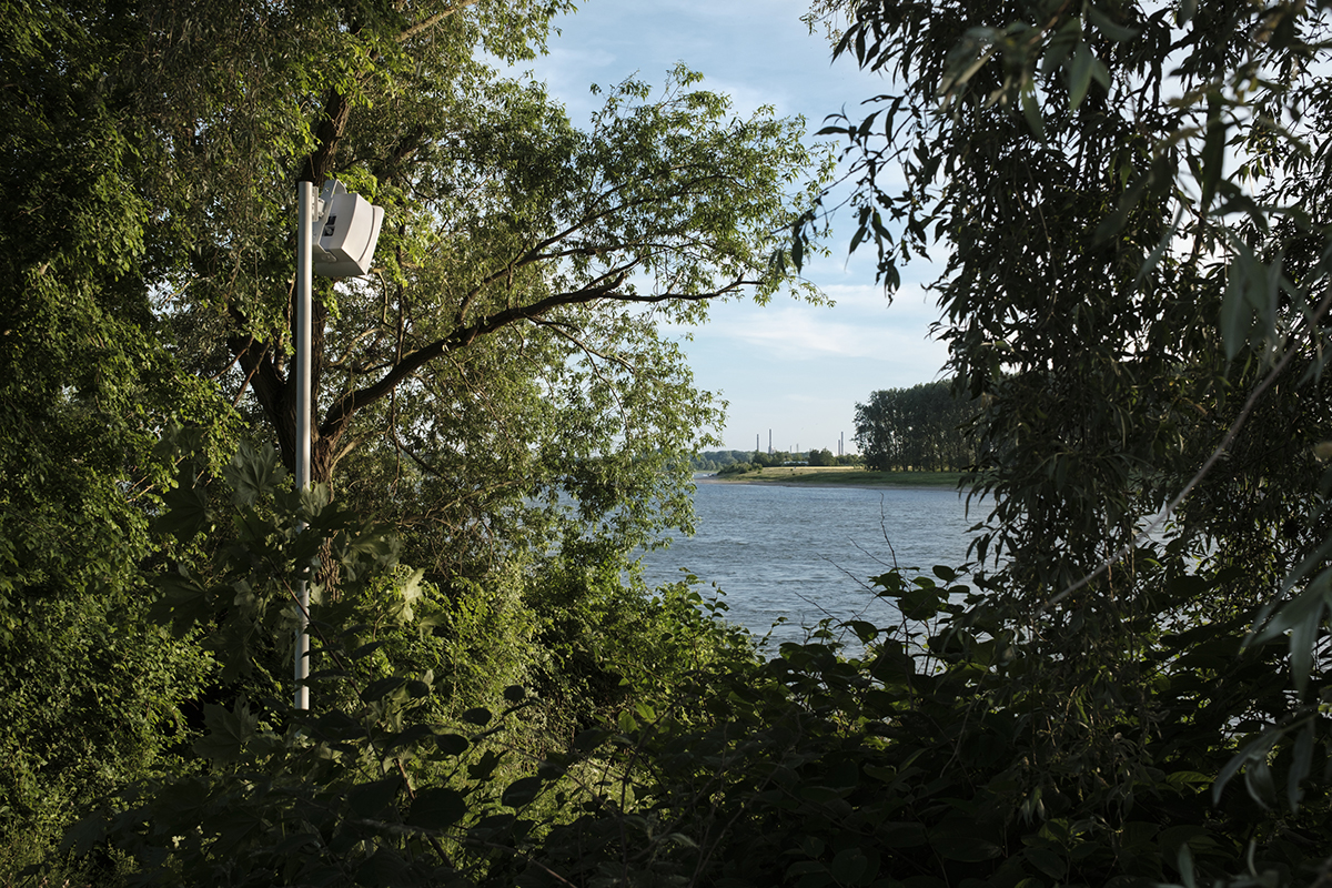 James Webb, A series of personal questions addressed to the River Rhine (2023) | Speakers, audio, dimensions variable | Installation view, Monheim Triennale, Monheim | link to audioIn this ongoing series, the artist literally poses spoken questions to selected objects and environments as if they were sentient beings able to respond. The installation takes the form of audio speakers installed above where the audience would ideally be situated in relation to the object or space. Each set of questions is written specifically for the chosen interview subject. No answers are written, given, or suggested, and a pause of approximately 10-seconds is taken between each question. In this pause, the object can be thought of as being in a state of response. Here too, the audience is also free to consider their own replies to the questions.