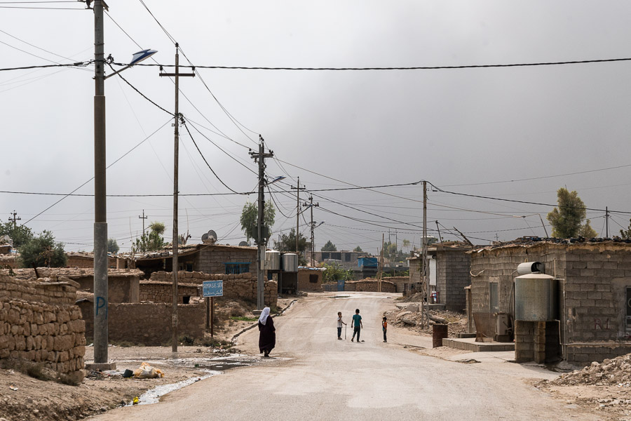 Camp de Maxmur, irak. Une des rues principales du camp. Le ciel est obscurcit par des fumées noires en provenance des combats autour de Mosul, à 100km.