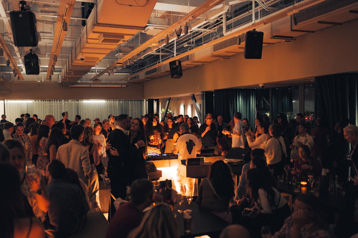 Close-up of Gilles Peterson smiling while DJing at the Paired × Tate Modern event, surrounded by guests enjoying the night