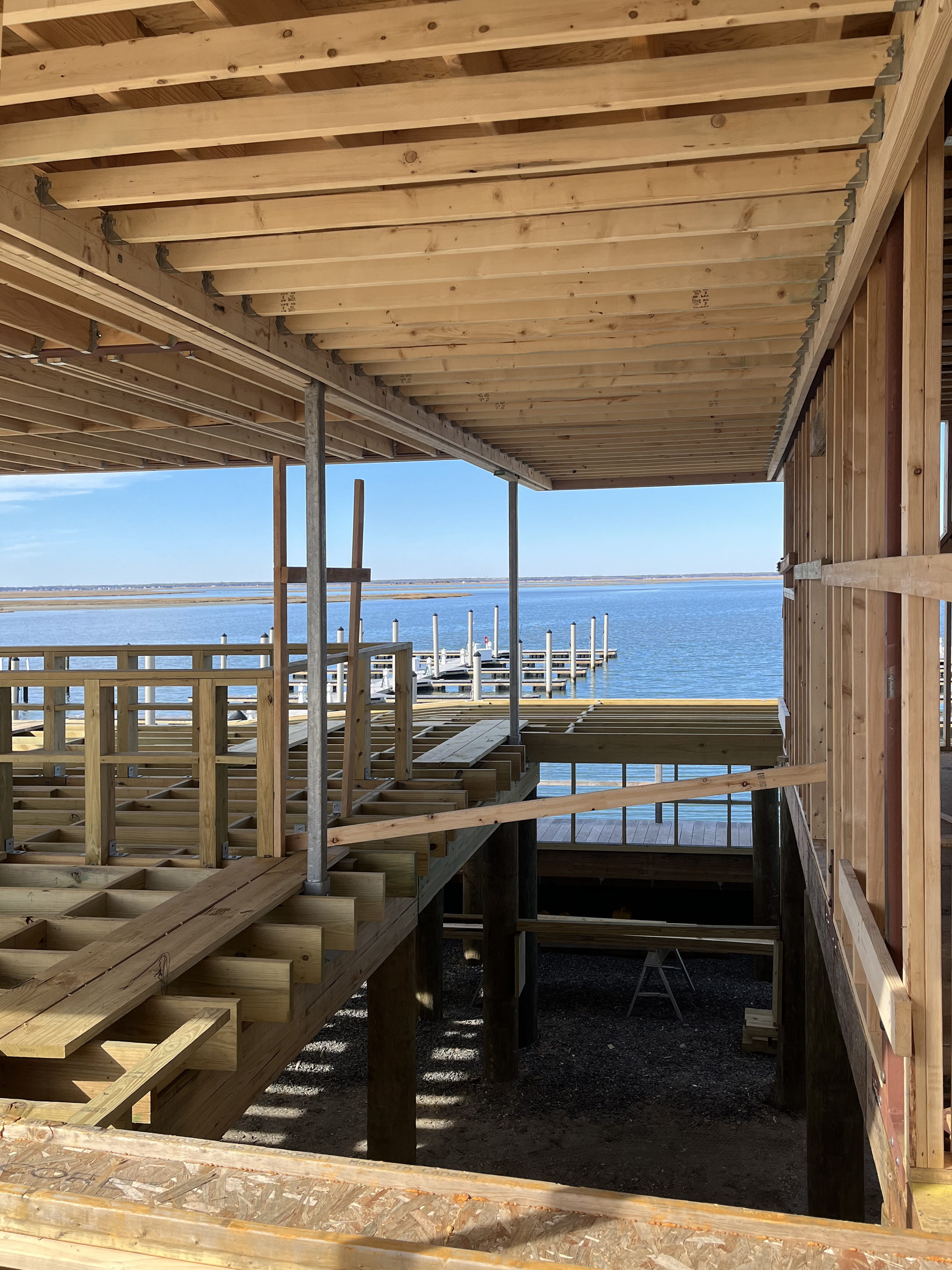 Wide construction progress photo showing the large elevated deck and surrounding wood framing that will form the pool and sun deck area of the Paddle Club.