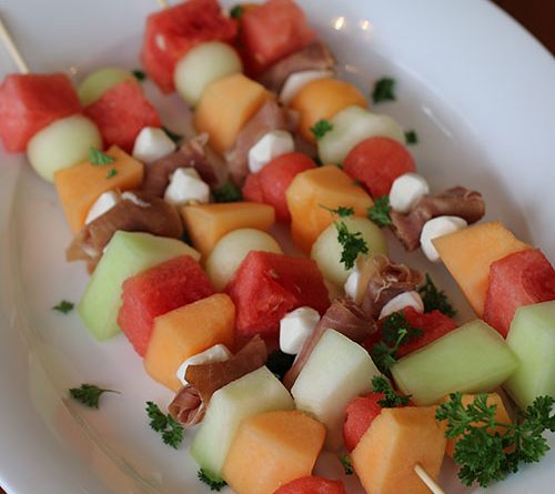 An up-close picture of colorful skewers of Prosciutto and Melon