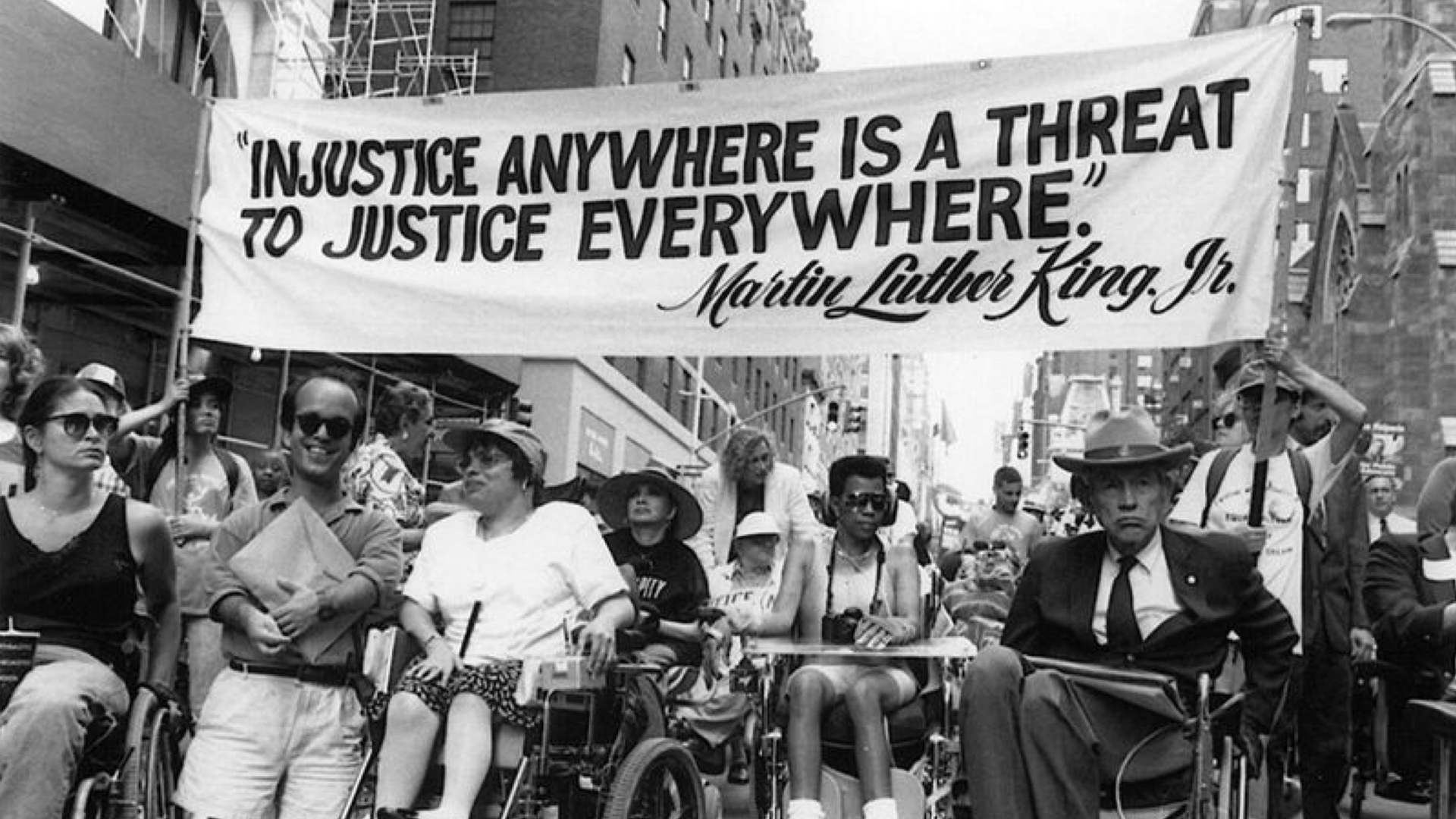 Historical documentation of the 504 disability rights protest in April of 1977, including the banner, "injustice anywhere is a threat to justice everywhere," a quote by MLK Jr.