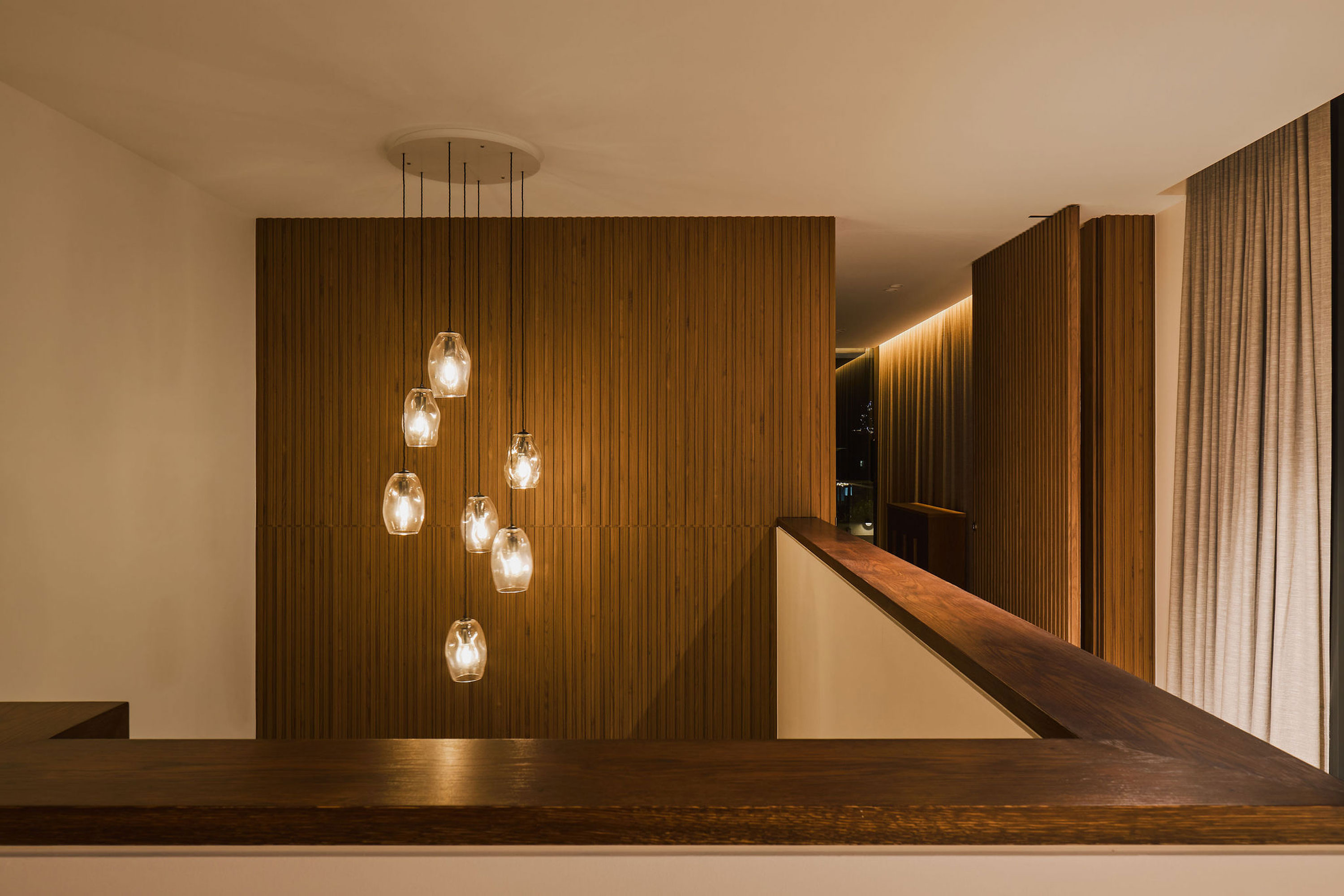 A wooden-walled hallway illuminated by a decorative chandelier above.