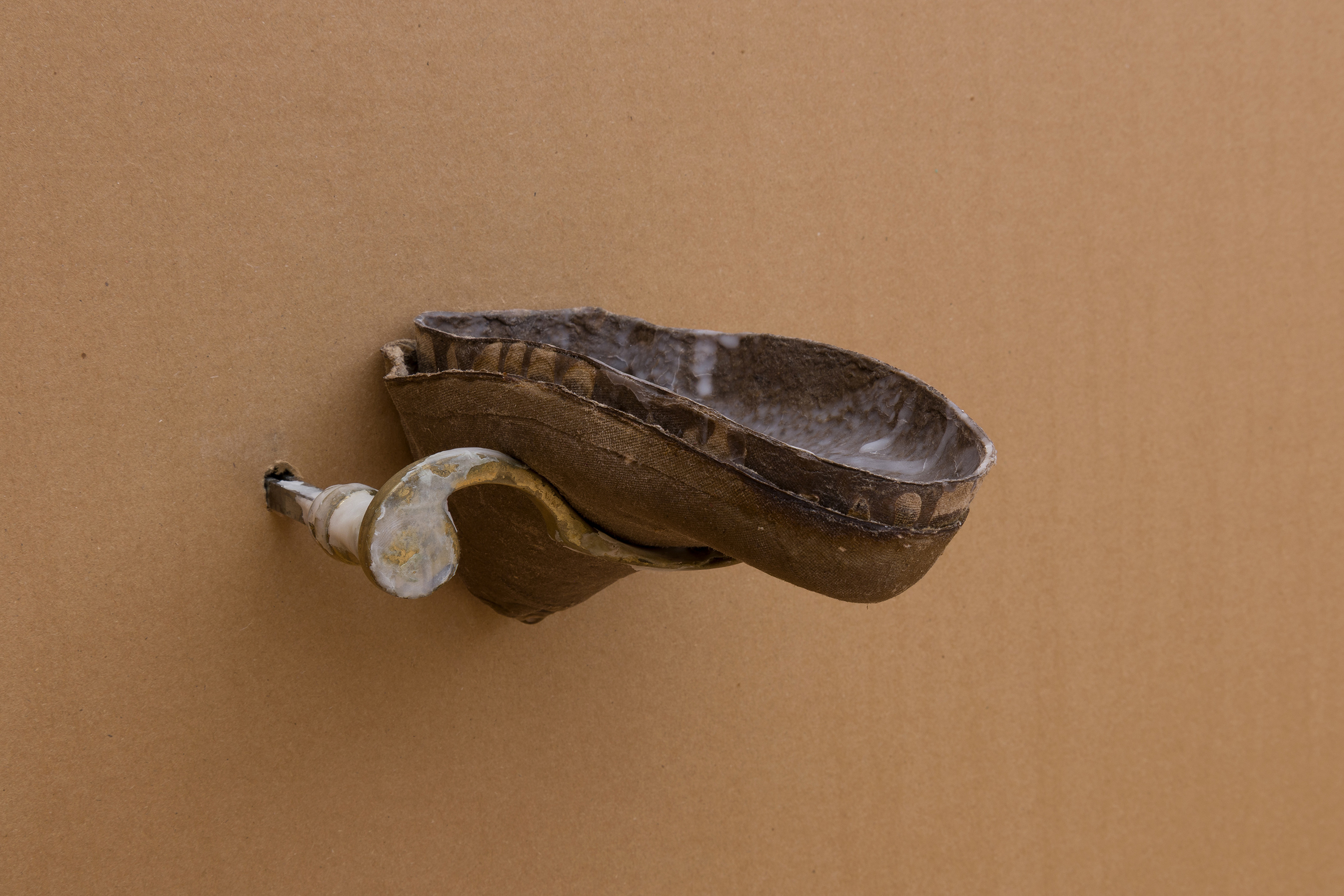 All Of My Shoes (Tempo), 2025. Old brass door handle with traces of air-dry porcelain; cardboard shoe insert with beeswax, raw cardboard shoe insert, piezo microphones, water dripping system.