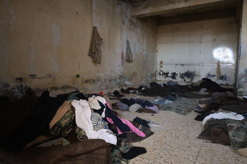 Inside a cell at Sednaya Prison, a pile of clothes and bedding have been left behind by liberated detainees.