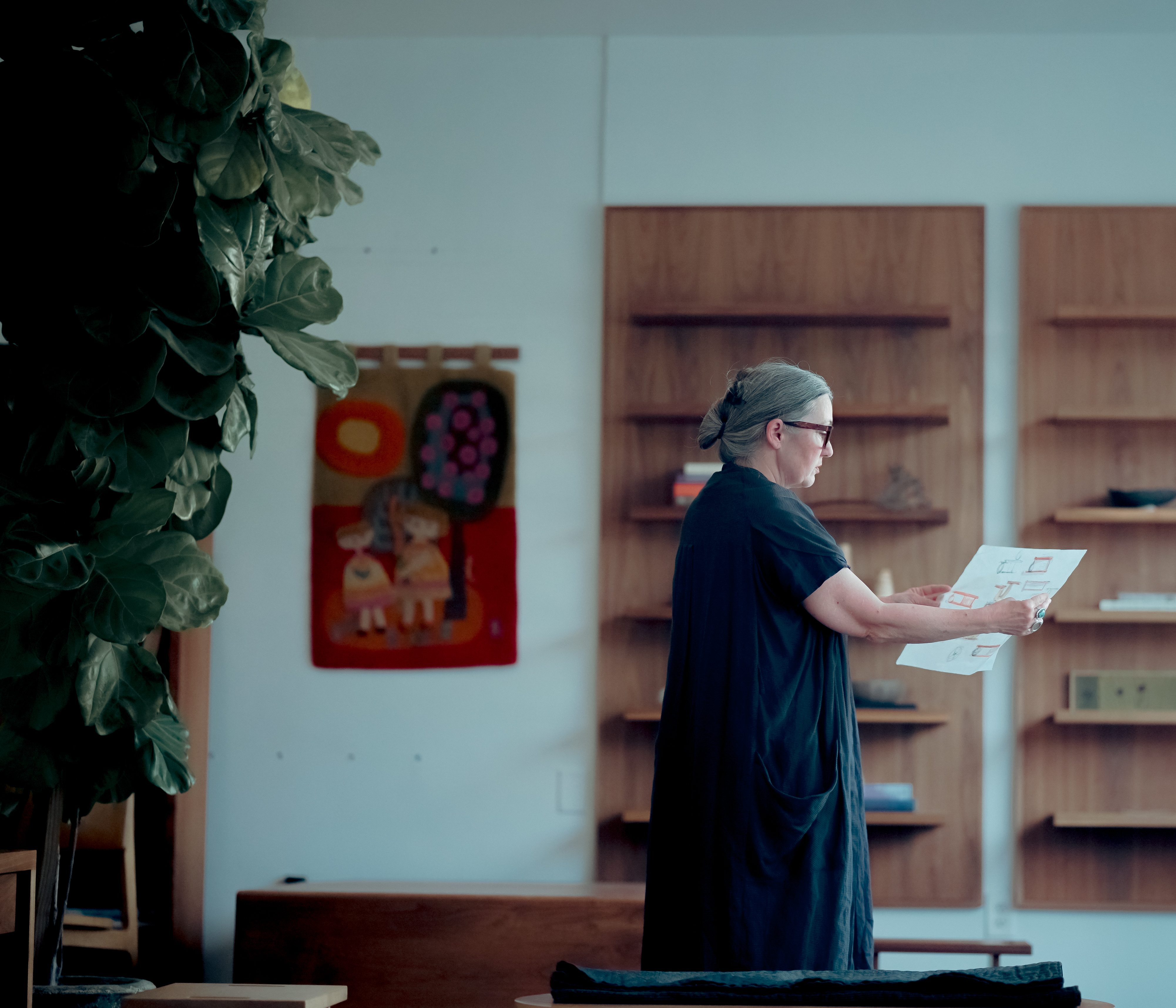 Leslie holds tracing paper of furniture sketches in her studio.