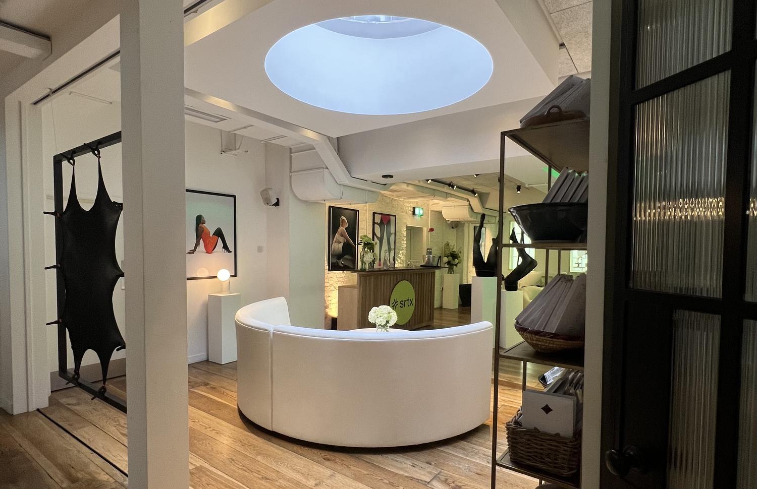 Sheertex showroom interior with circular white sofa, branded counter, and tights art displays.