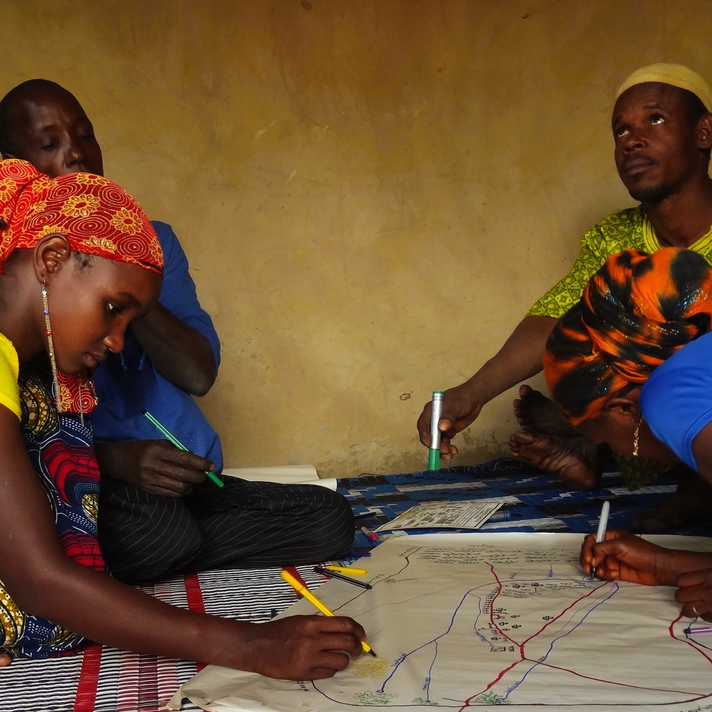Après intervention de la part des animateurs de l'atelier, les femmes, jusqu'alors en retrait, ont pu avoir accès aux feutres pour participer à la carte.
