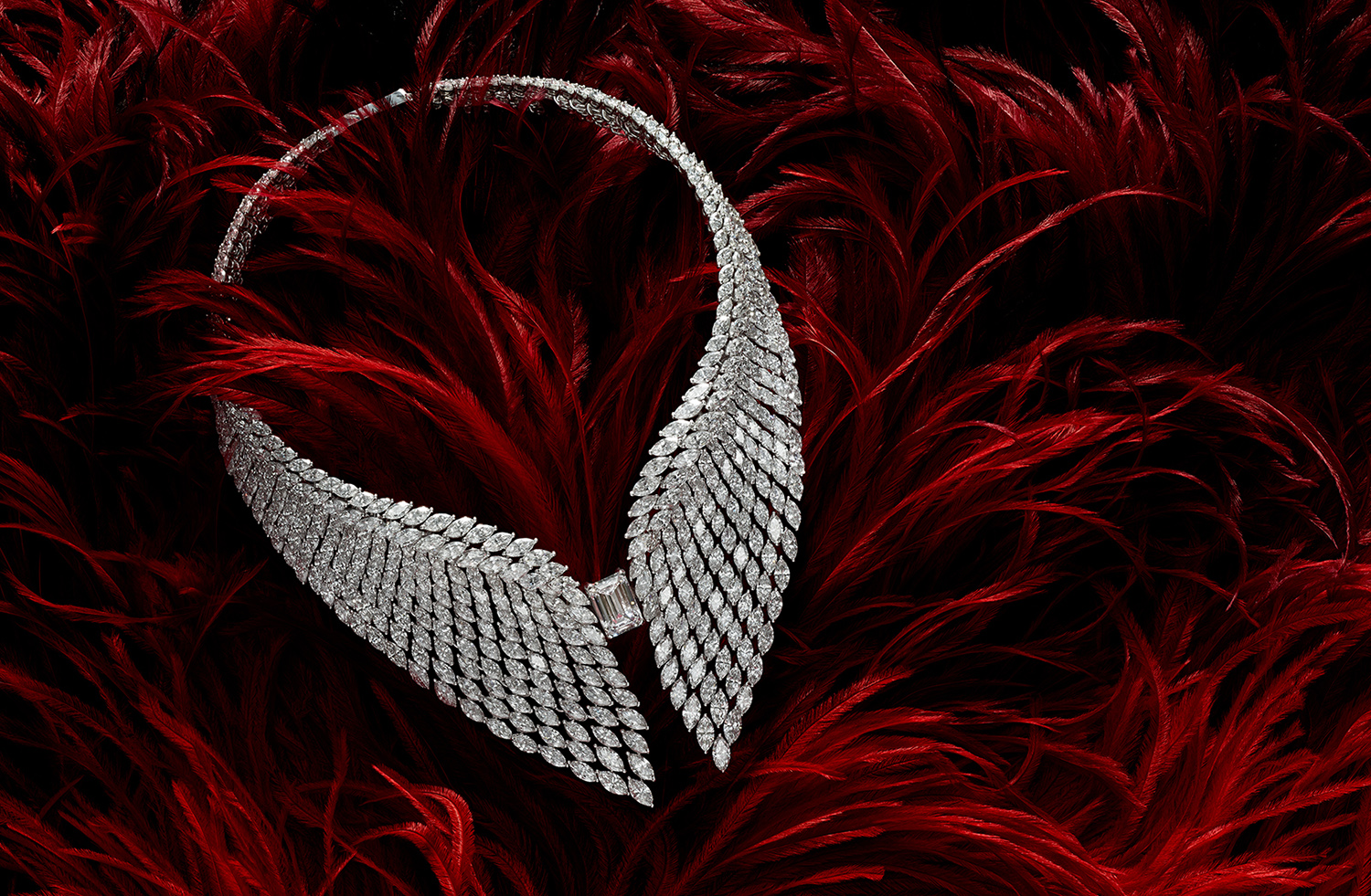 KMA photographer Isabelle Bonjean photographs diamond necklace laying on red feathers for Messika