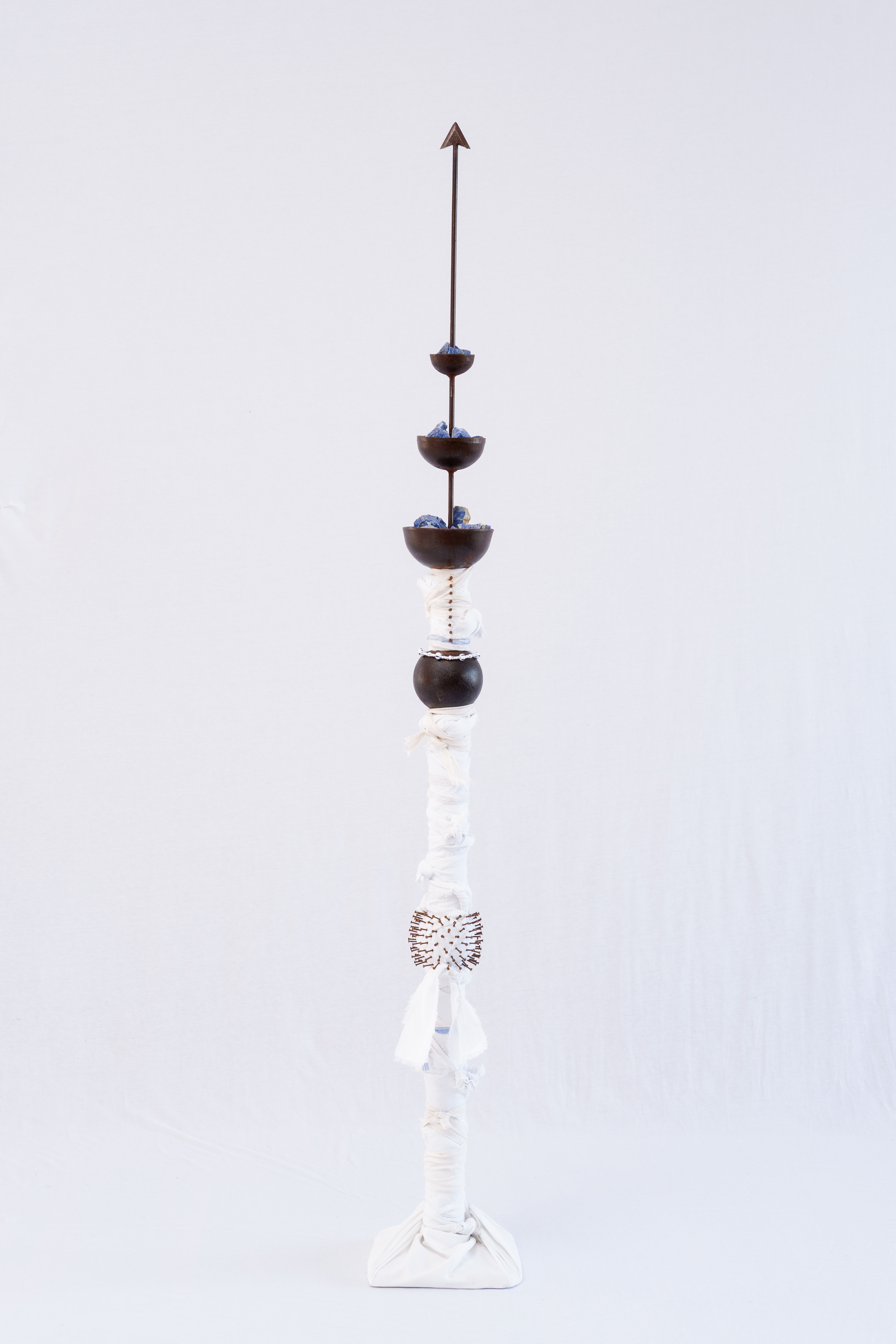 THE BEADS OF MY ROSARY ARE ARTILLERY BULLETS (1)Iron, lapis lazuli, fabric and glass. 198 x 51 x 51 cm. 2024