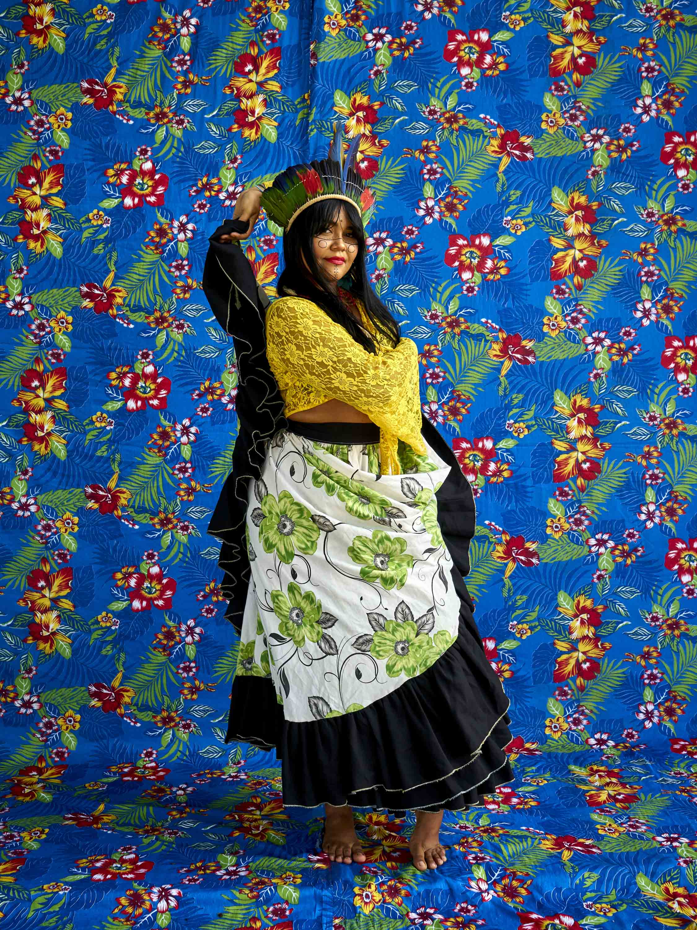 Thaline Karajá, the voice of the Suraras do Tapajós poses for a portrait in front of the fabrics that they use to make their skirts.