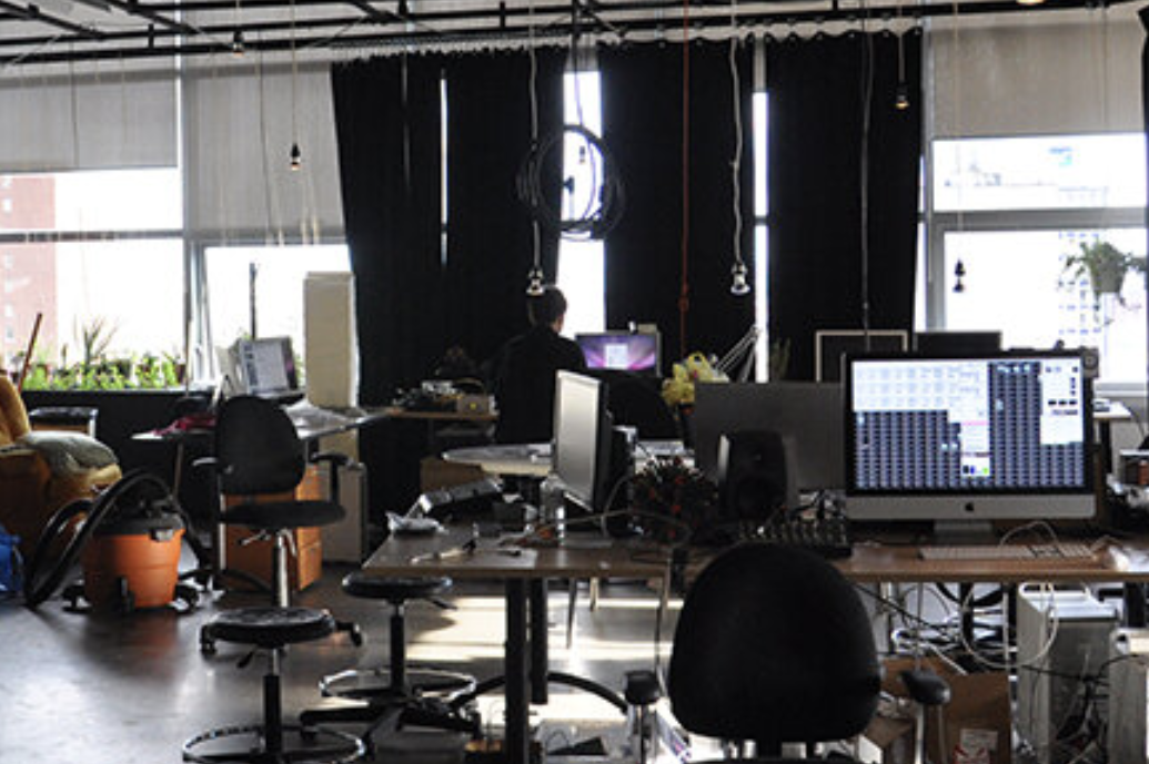 An office with several desks, computer and rolling chairs.
