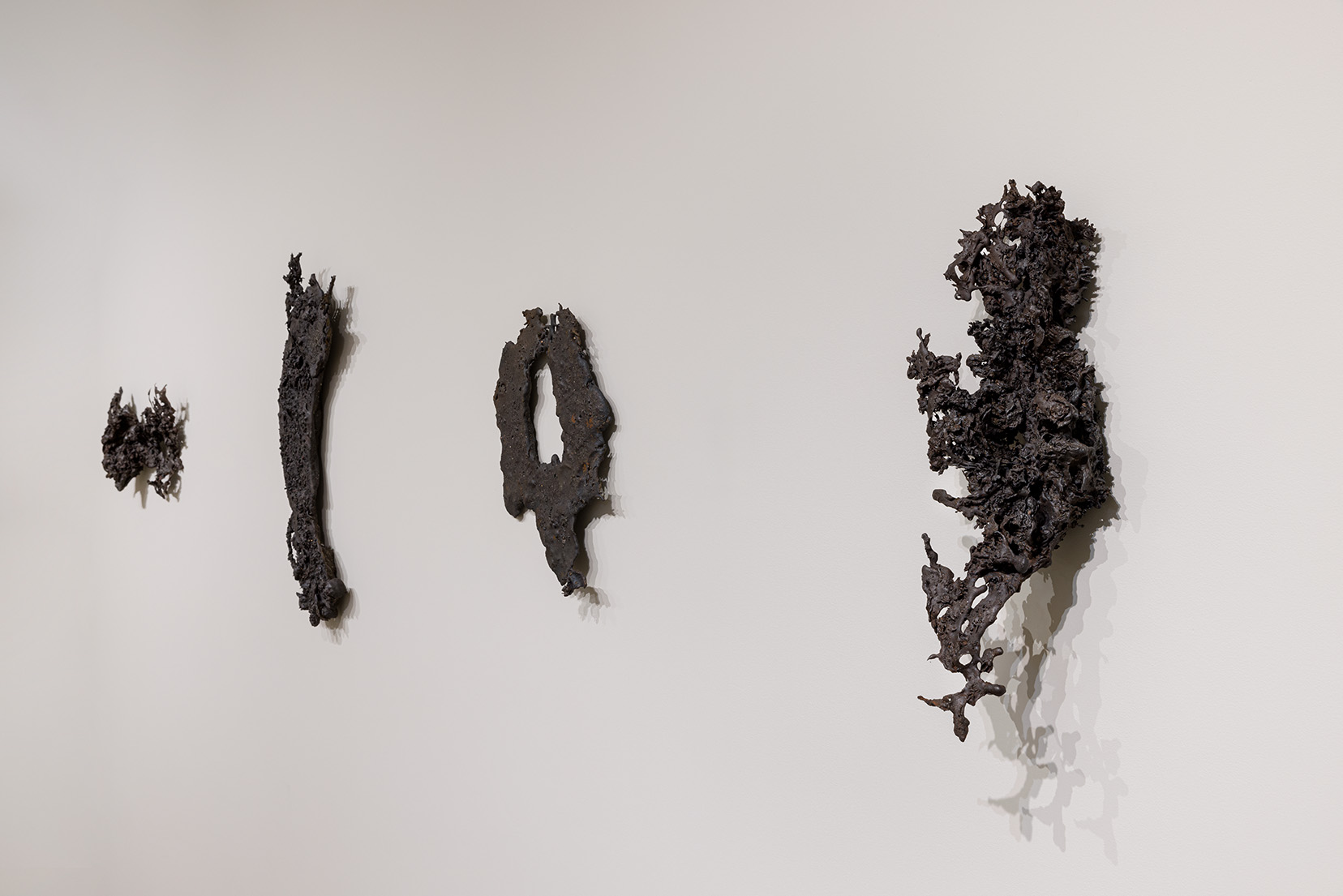 (From left to right) Athena LaTocha, "Mesabi #1," 2019. Cast iron, 17 1/4 x 13 3/4 x 2 3/8 inches; "Mesabi #4," 2019. Cast iron, 28 3/4 x 13 3/4 x 3 1/8 inches; "Mesabi #6," 2019. Cast iron, 11 1/4 x 19 3/4 x 3 3/8 inches; "Mesabi #7," 2019. Cast iron, 22 1/2 x 10 3/4 x 6 1/2 inches. Photo by Etienne Frossard.