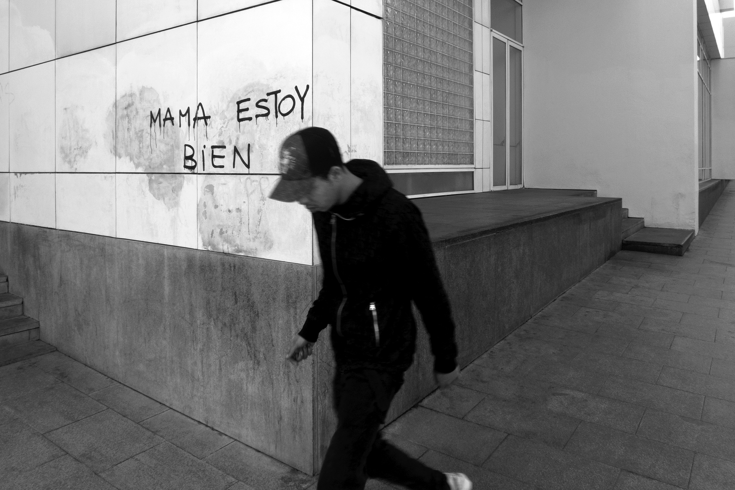 Young man passing by graffitiBarcelona, Spain, 2022photography, bw, single