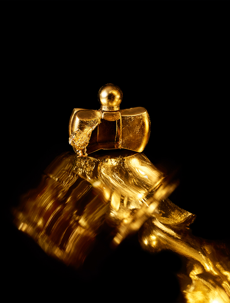 KMA photographer Isabelle Bonjean shoots a close up photograph of a bright gold perfume bottle for Faux Q Magazine