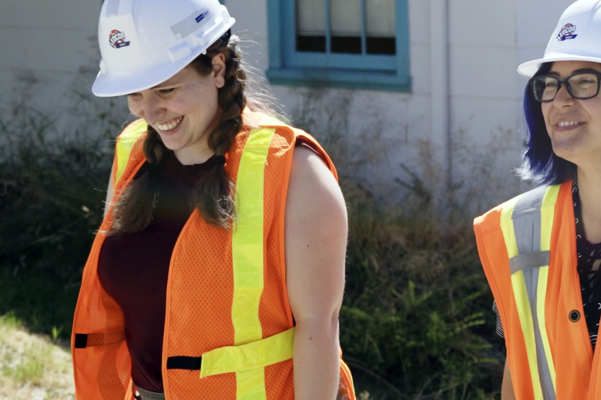 Two young women in safety gear walk smiling