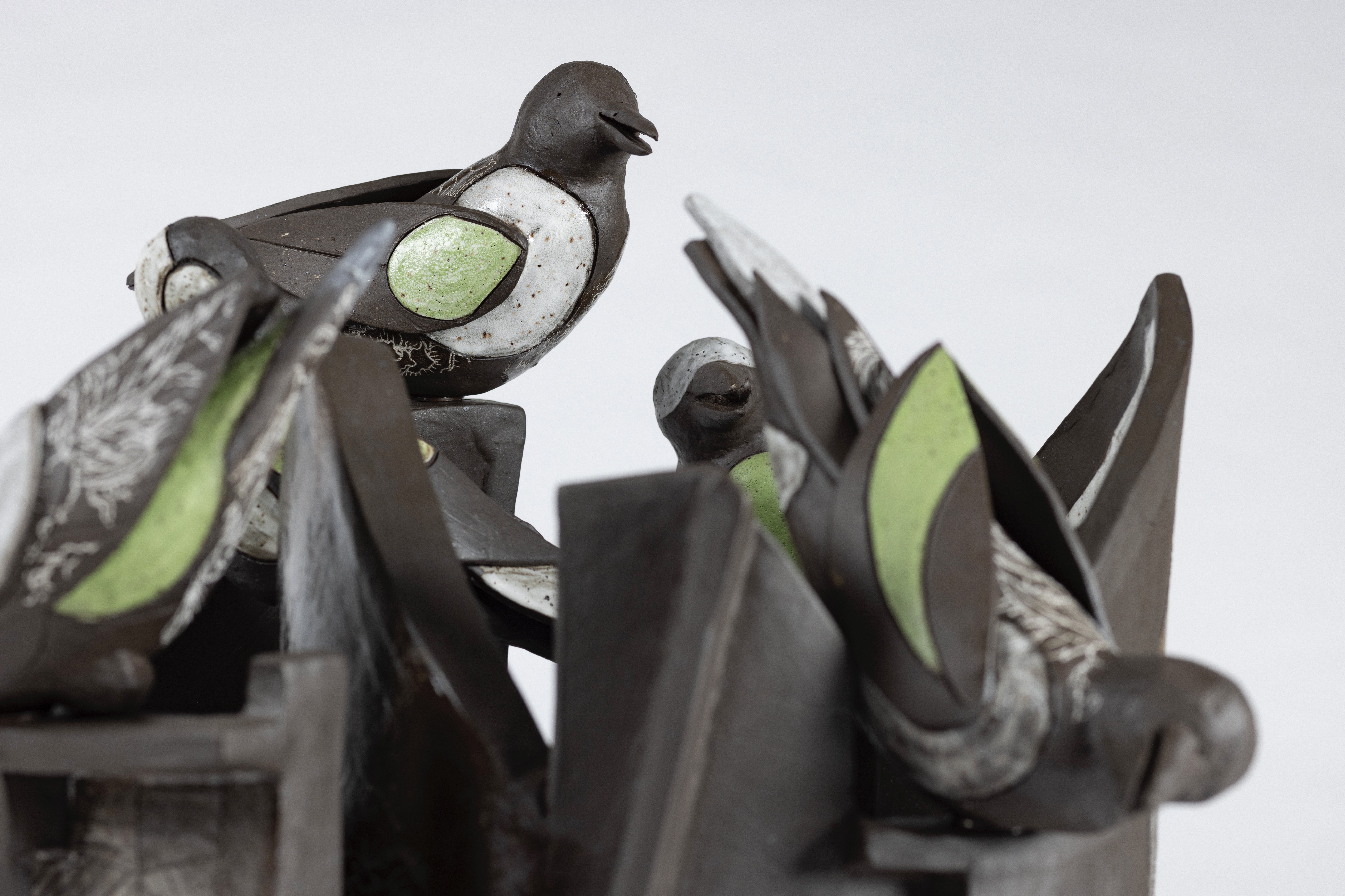 Lydia Thompson, Bird Formation #3, 2024. Ceramics with transfers, 16 x 16 x 16” (detail). Two brown birds with mint colors on their wings perched on jagged pieces representing urban detritus.