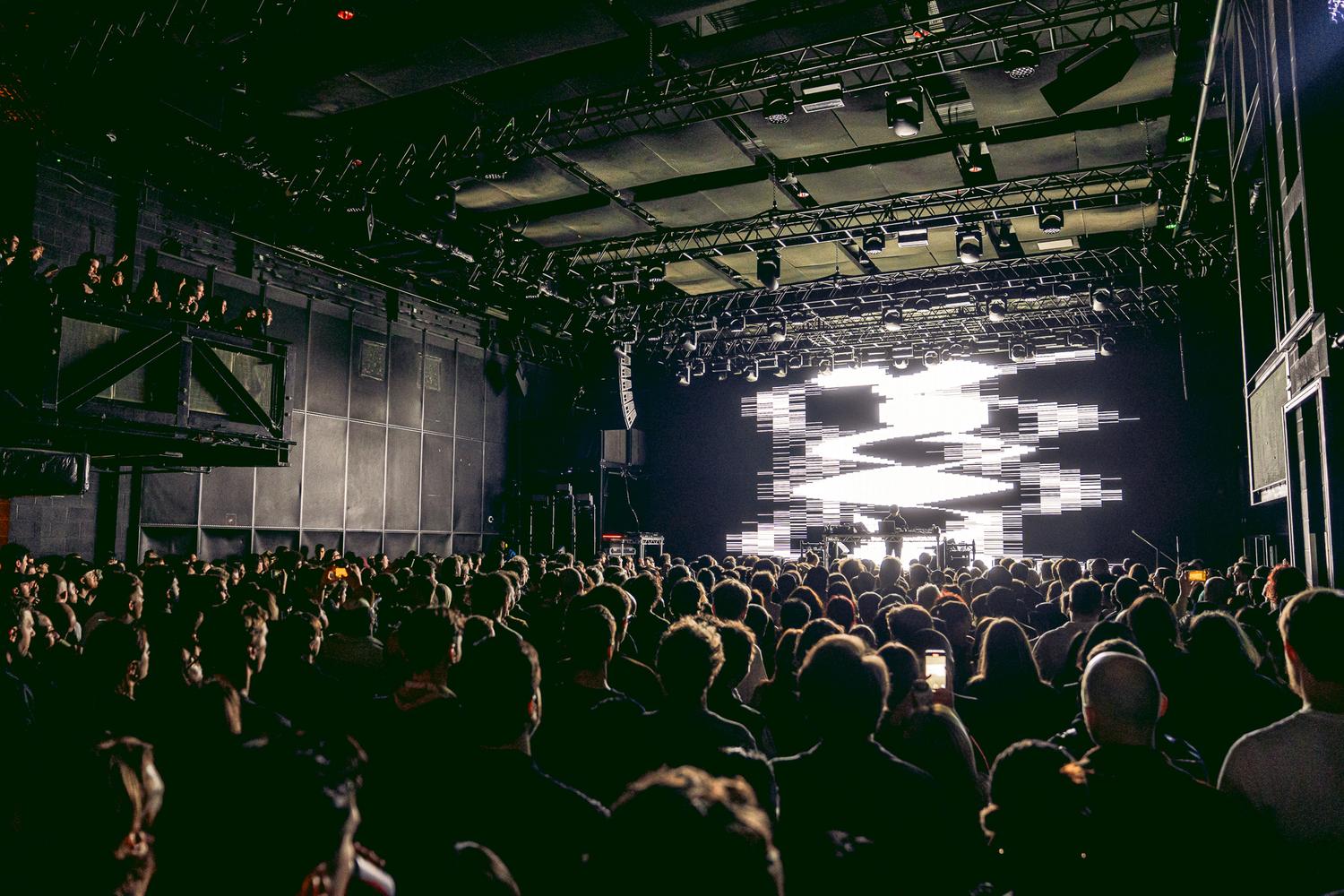 Ryoji Ikeda performing at HERE at Outernet for AVA London with abstract black-and-white visuals and packed audience.