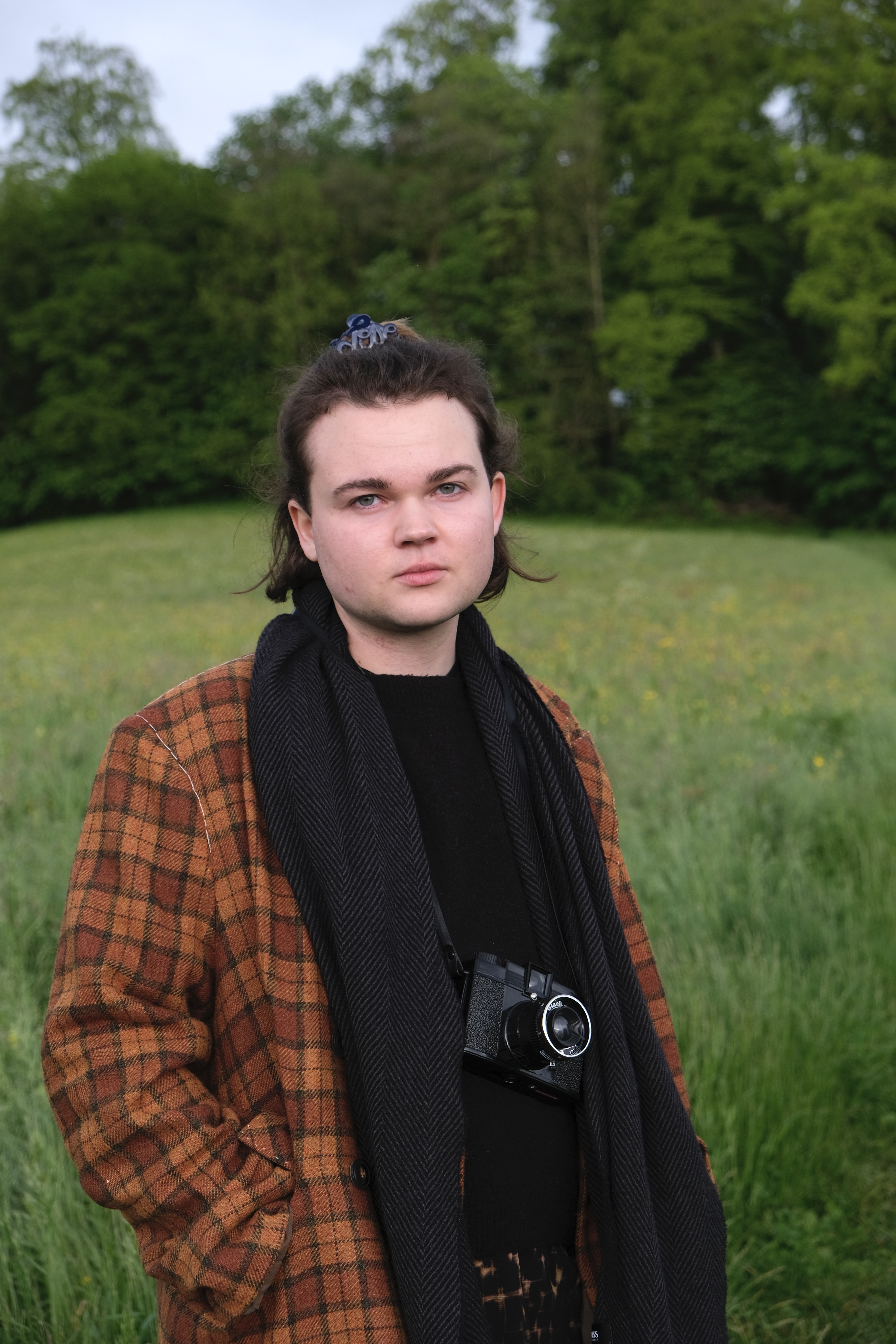 picture of Vincent Mugg in a field with a camera around his neck.