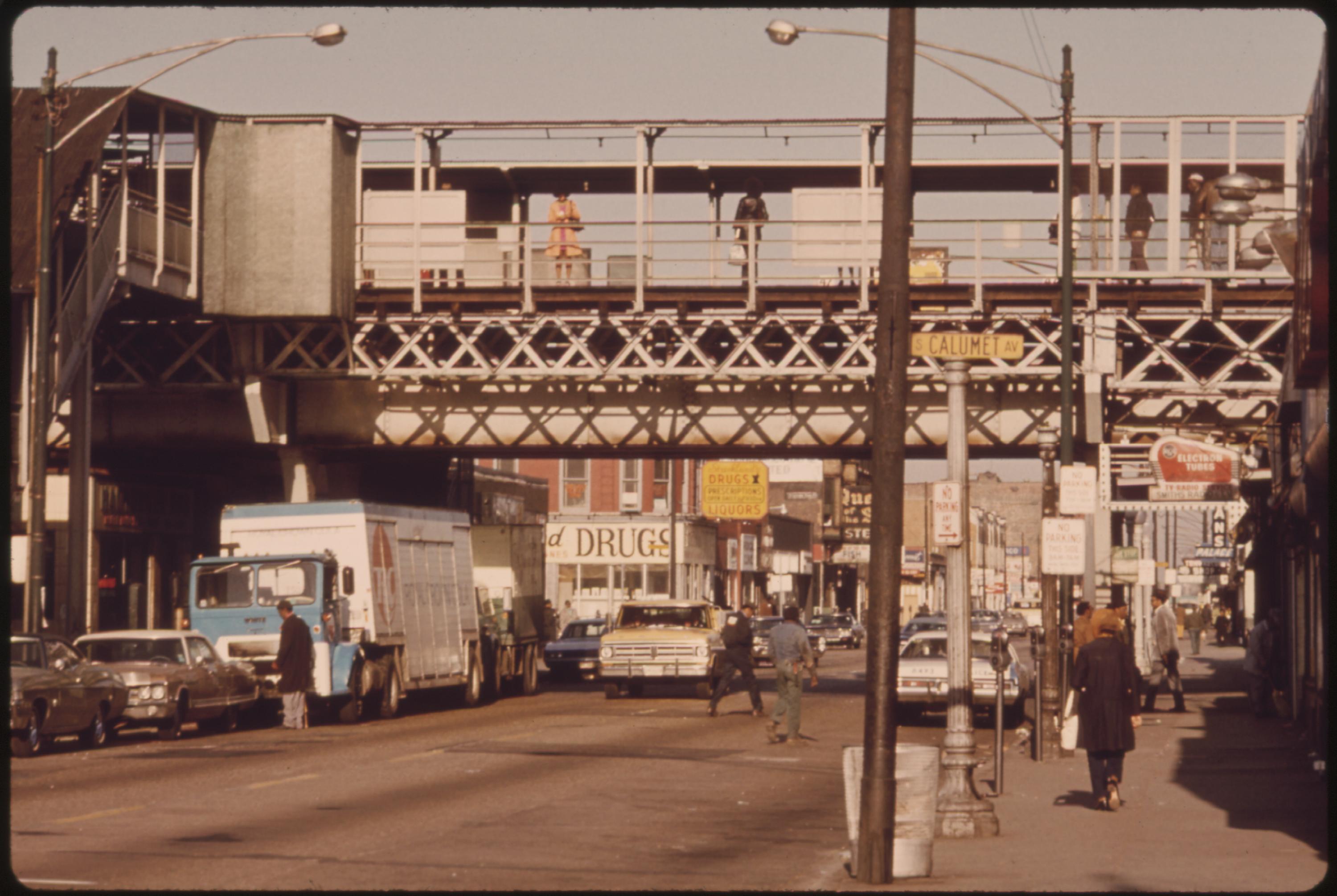 Once one of Chicago’s busy thoroughfares, 63rd Street has changed with the character of the city. Many fires have resulted [in] driving out more businesses which either follow the flight of other stores to more prosperous areas or cease to exist. The “El” (elevated train) tracks are seen in the upper portion of the picture. During 1973 the Chicago Transit Authority reported 95,160,535 passengers used the facilities, July 1973.