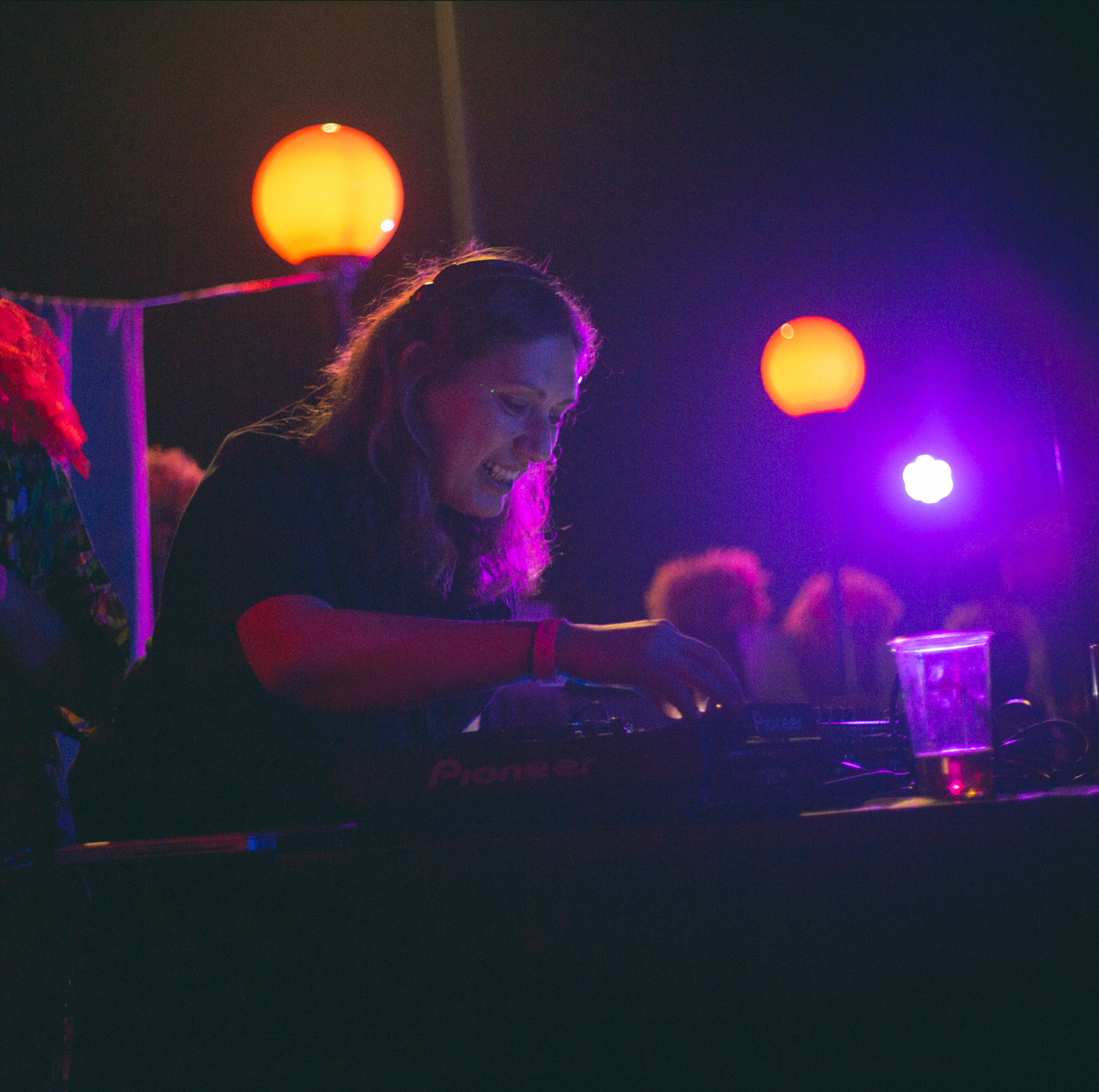 [IMAGE DESCRIPTION]: portrait of Şevval djing at a party, surrounded by purple and orange lights.
