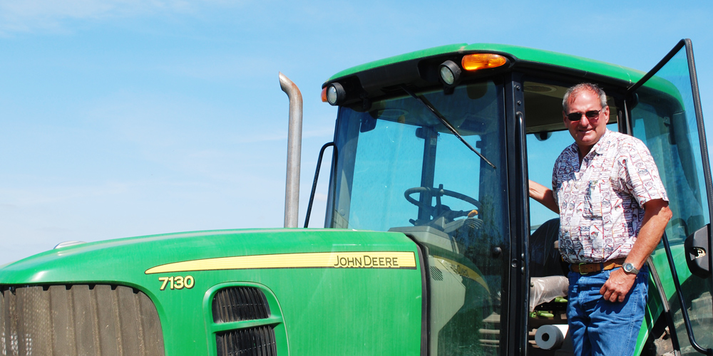 Farmer stepping out of a tractor in front a of clear, light-blue sky
