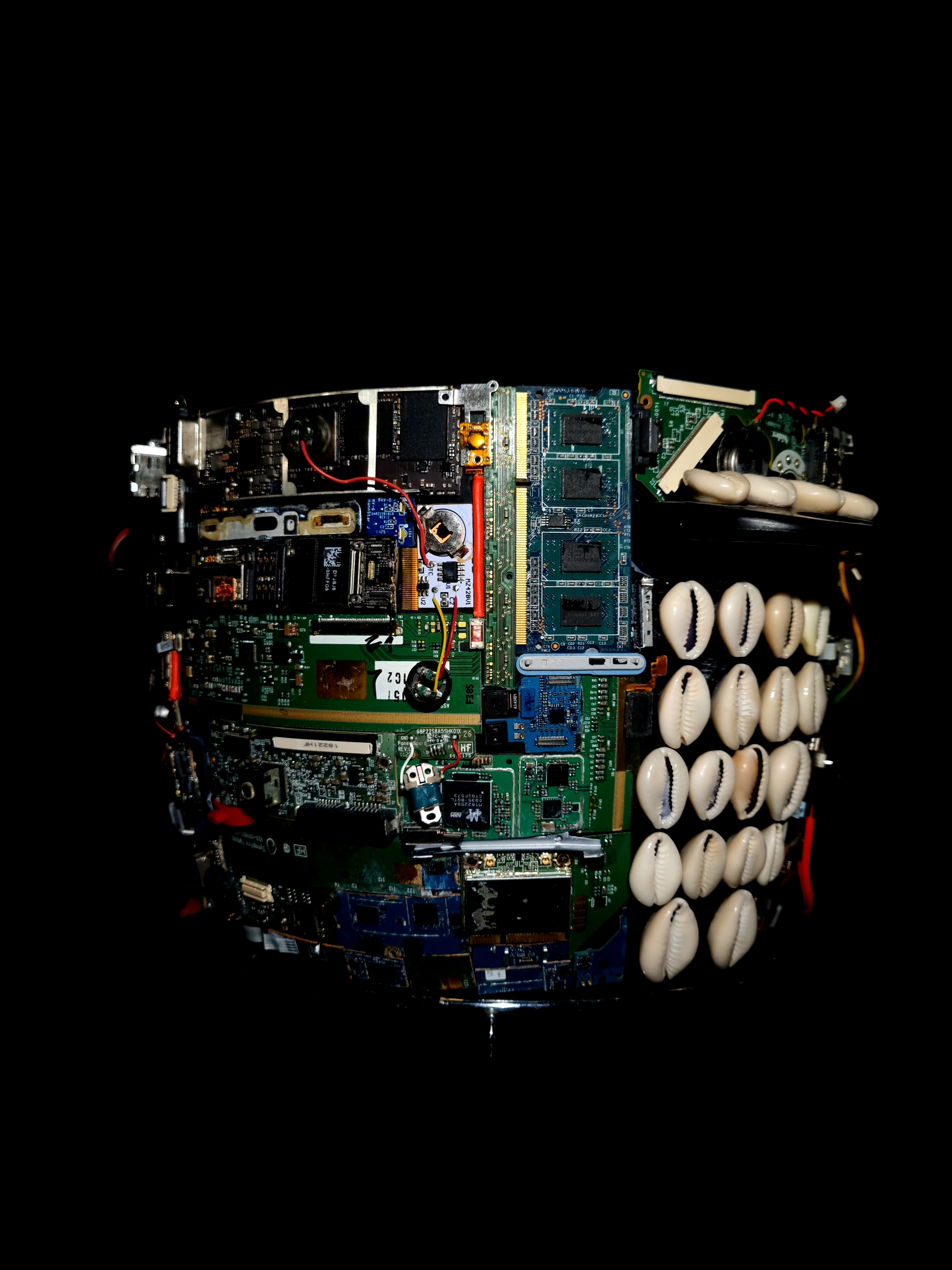 Nzúngu Ampûngu (2022) 17 x 66 cm. Circuit boards, e-components, clay, cowrie shells on found rice cooker