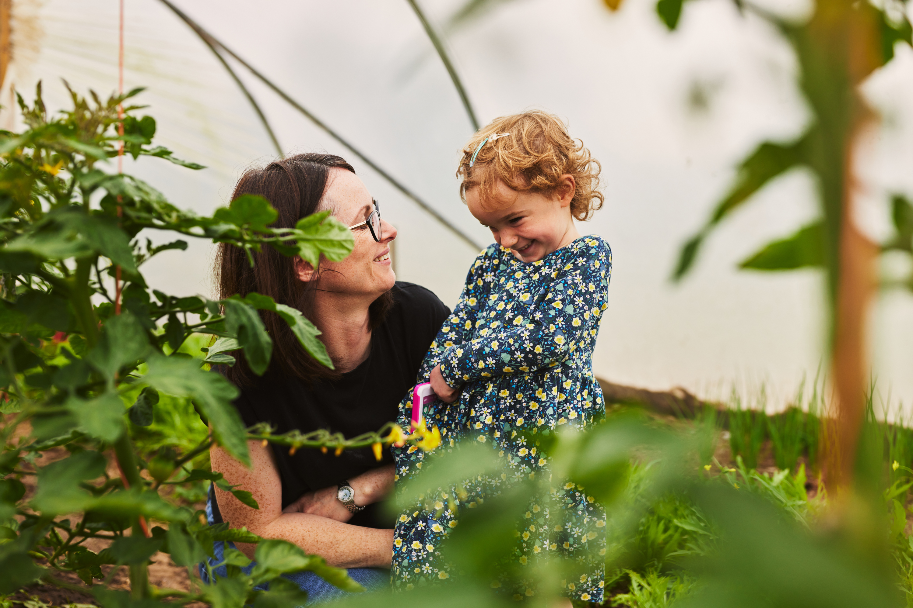 Lifestyle photography of a Spotify employee working in tech photographed working from home in Ireland for recruitment campaign, on their home farm with her daughter laughing and smiling