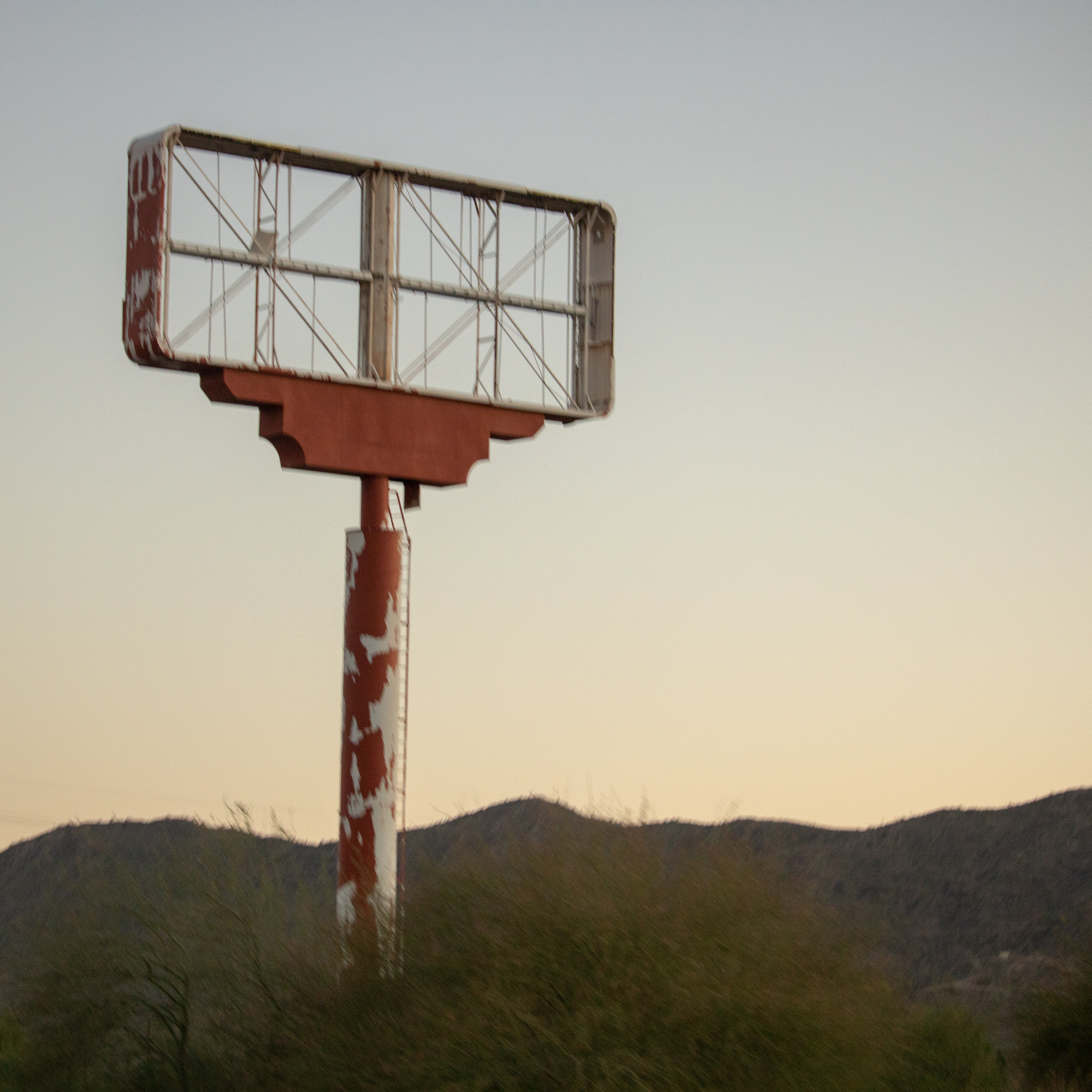 A weathered and abandoned billboard stands in Tucson, Arizona, representing urban decay and the passage of time in the desert landscape.