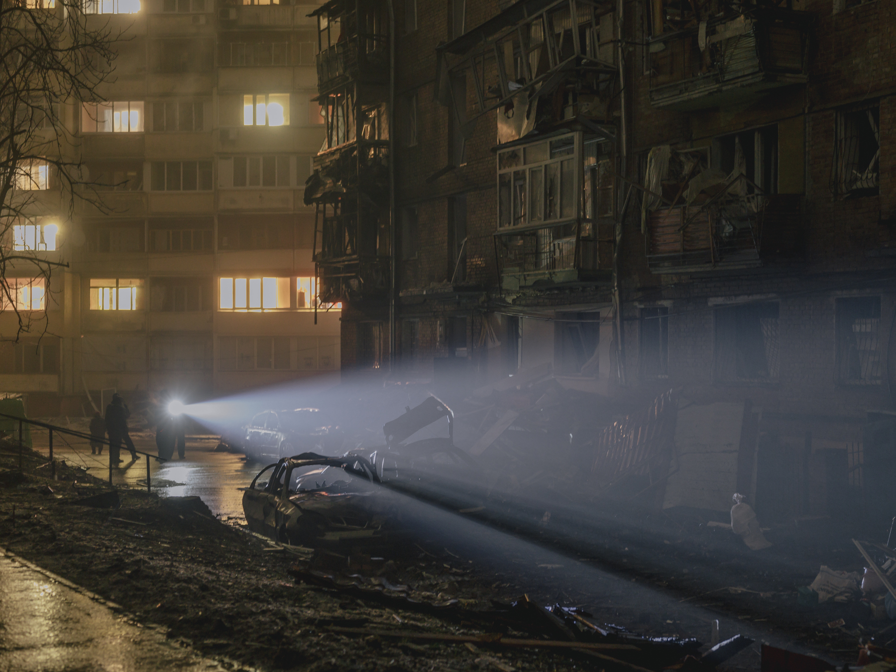 Police officers and residents watch a civilian house destroyed by Russian missile fire in the Vyshhorod neighborhood on the evening of November 24, 2022. More parts of the building keep collapsing. Kyiv Oblast, Nov. 24, 2022.