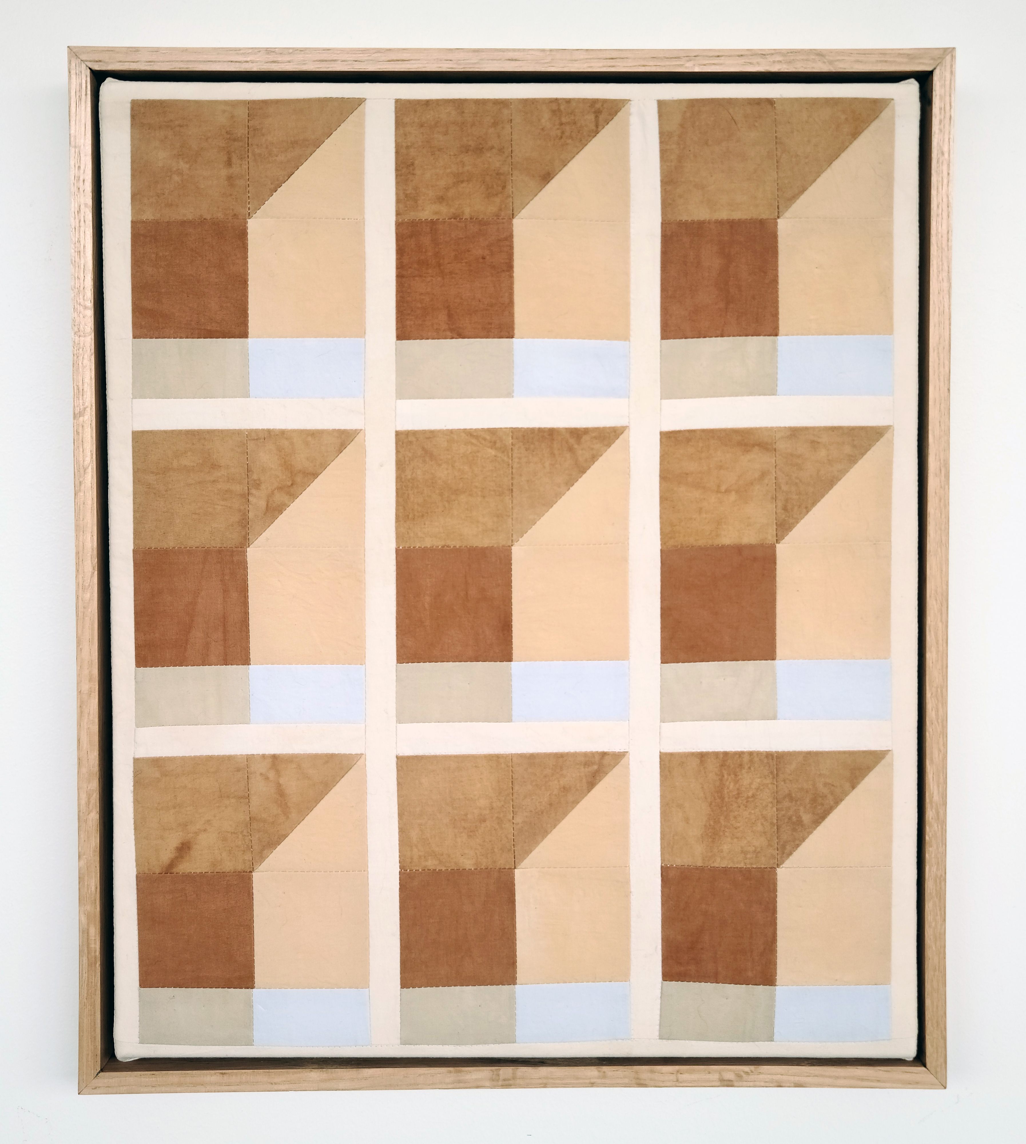 Textile quilt of 3 by 3 squares with brown, grey and light blue tiles in each square separated by light brown rows and columns.
