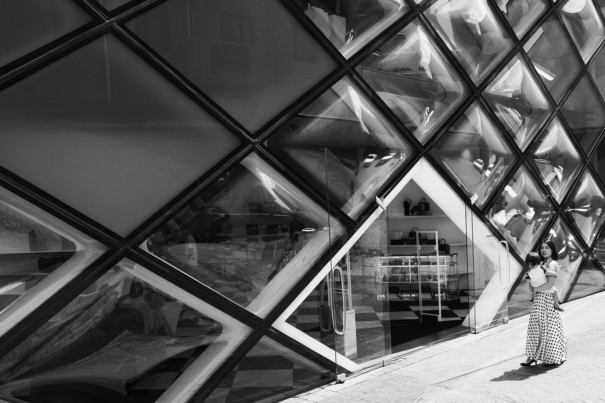 Philippe Sarfati-Territories-photography-photographer-street-documentary-architecture-black-and-white-prada-aoyama-store-herzog-de-meuron-tokyo-japan-classy-woman-baby-dress-polka-dots-grid-facade-losange-glass-curved-futuristic-building