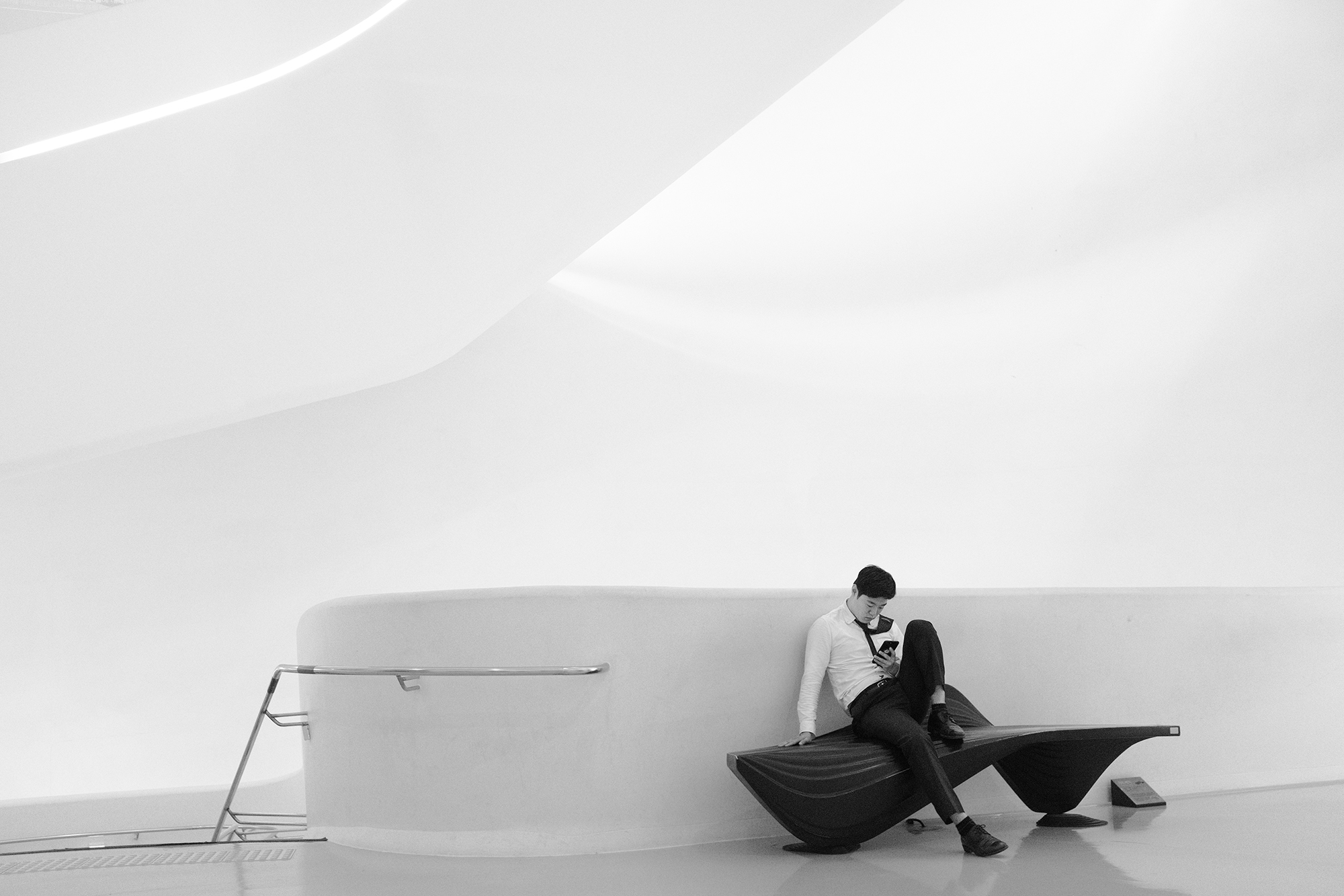 Philippe Sarfati-Territories-photography-photographer-street-documentary-architecture-black-and-white-zaha-hadid-architects-ddp-dongdaemun-design-plaza-seoul-south-korea-white-curvy-staircase-futuristic-minimalist-geometry-bench-custom-man-resting-tie-shoulder