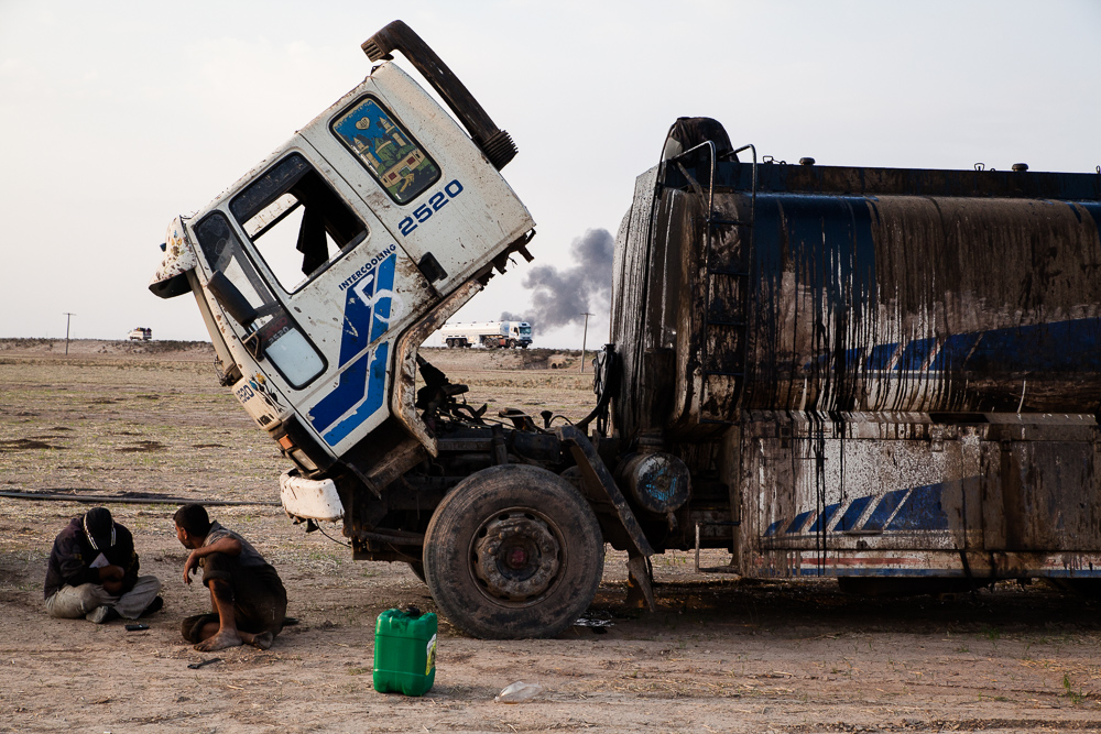 Les camions amènent le brut. Le produit du raffinage est stocké dans des bidons chargés dans des camionnettes.
