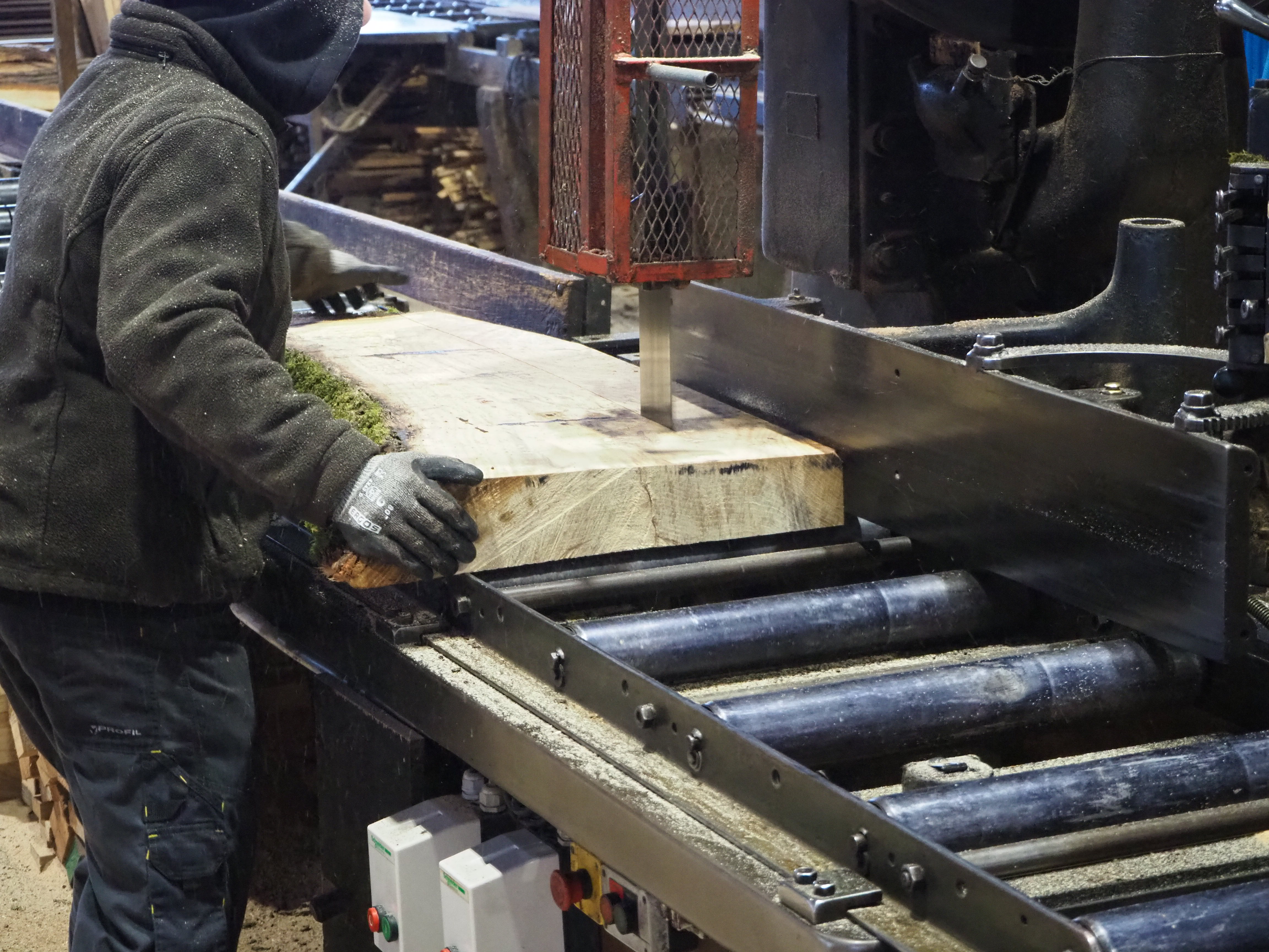 Une planche est débitée manuellement avec une plus petite scie à ruban 