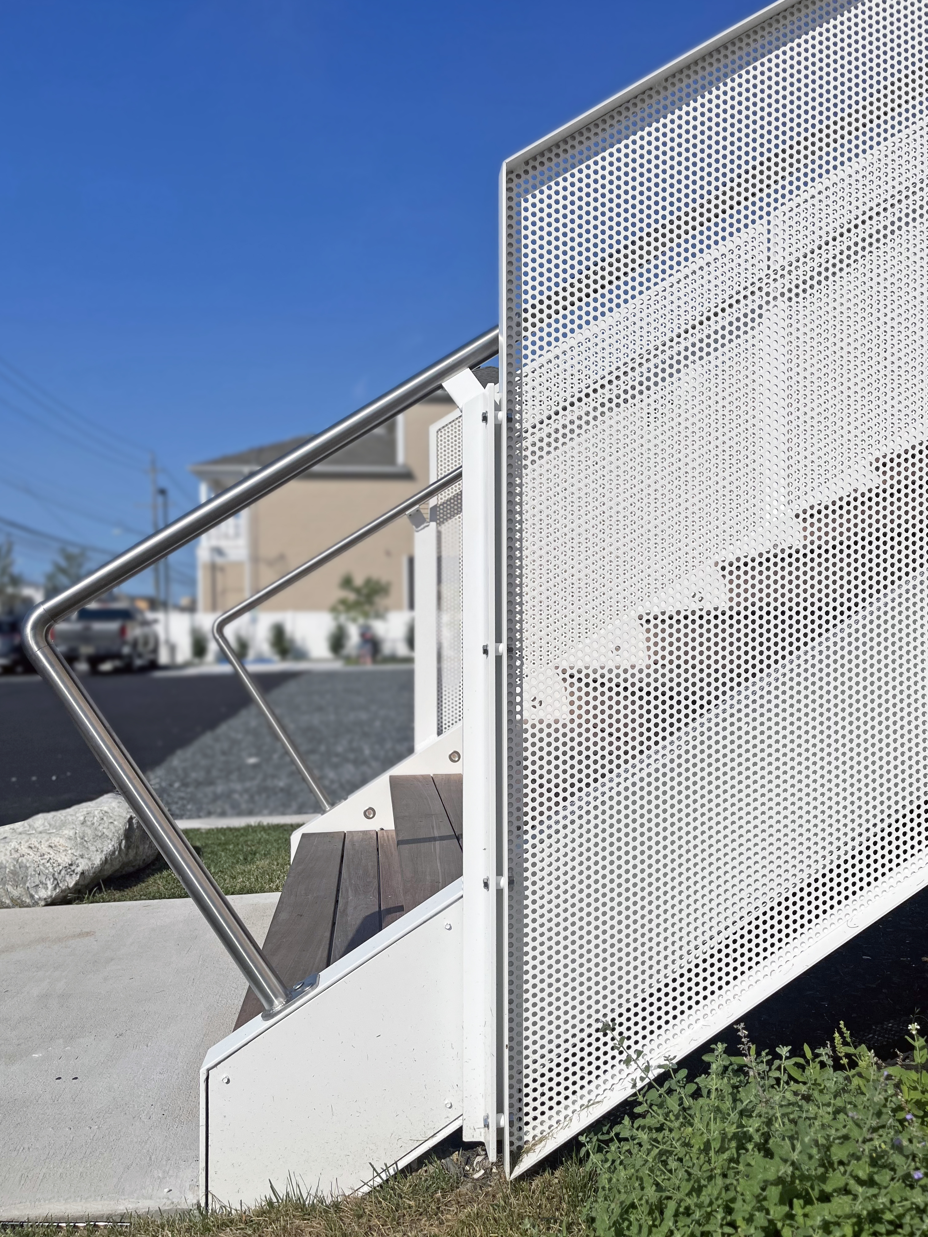 Close-up construction photo showing the modern main entry stair detail at the Brigantine Marina Paddle Club, featuring white perforated metal railings and wood treads.
