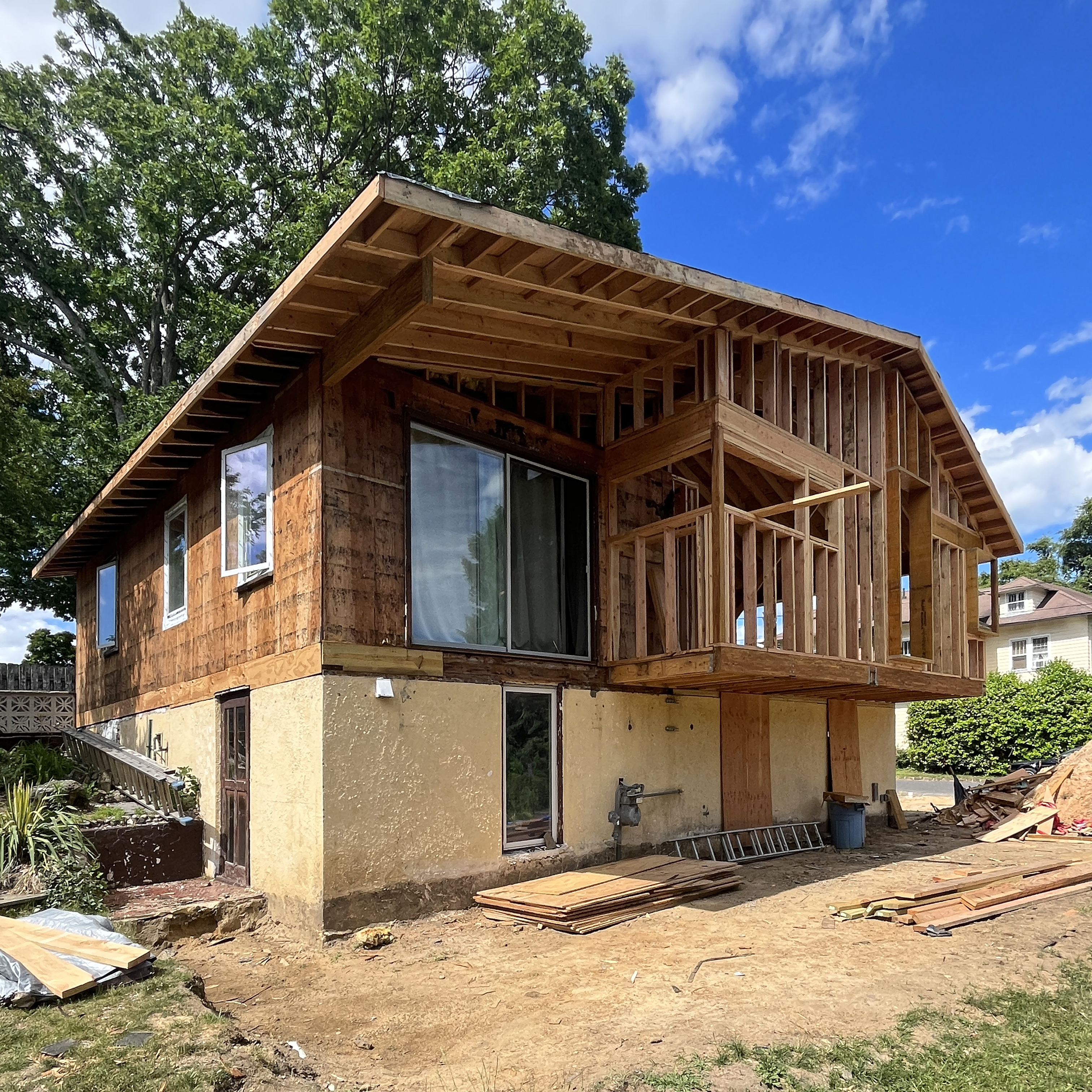Front view of the Atlantic Highlands Ranch Reno during construction, showing the exposed wood sheathing and partial installation of the new exterior cladding panels.