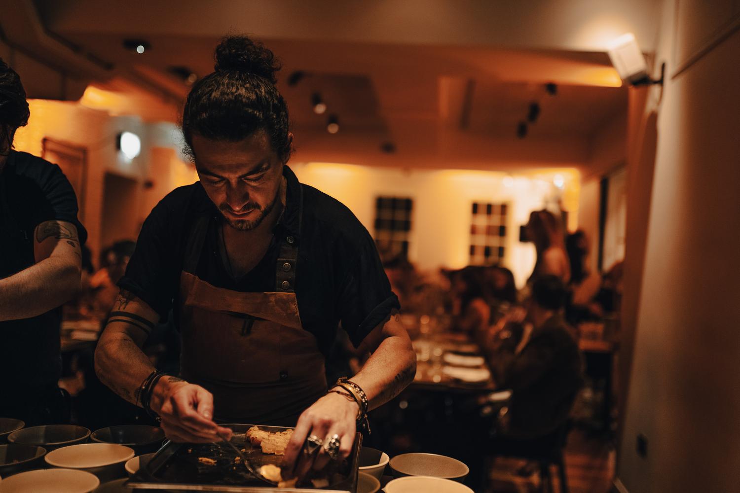 Chef focused on plating dishes under warm lighting during a Paired dinner at Carousel London
