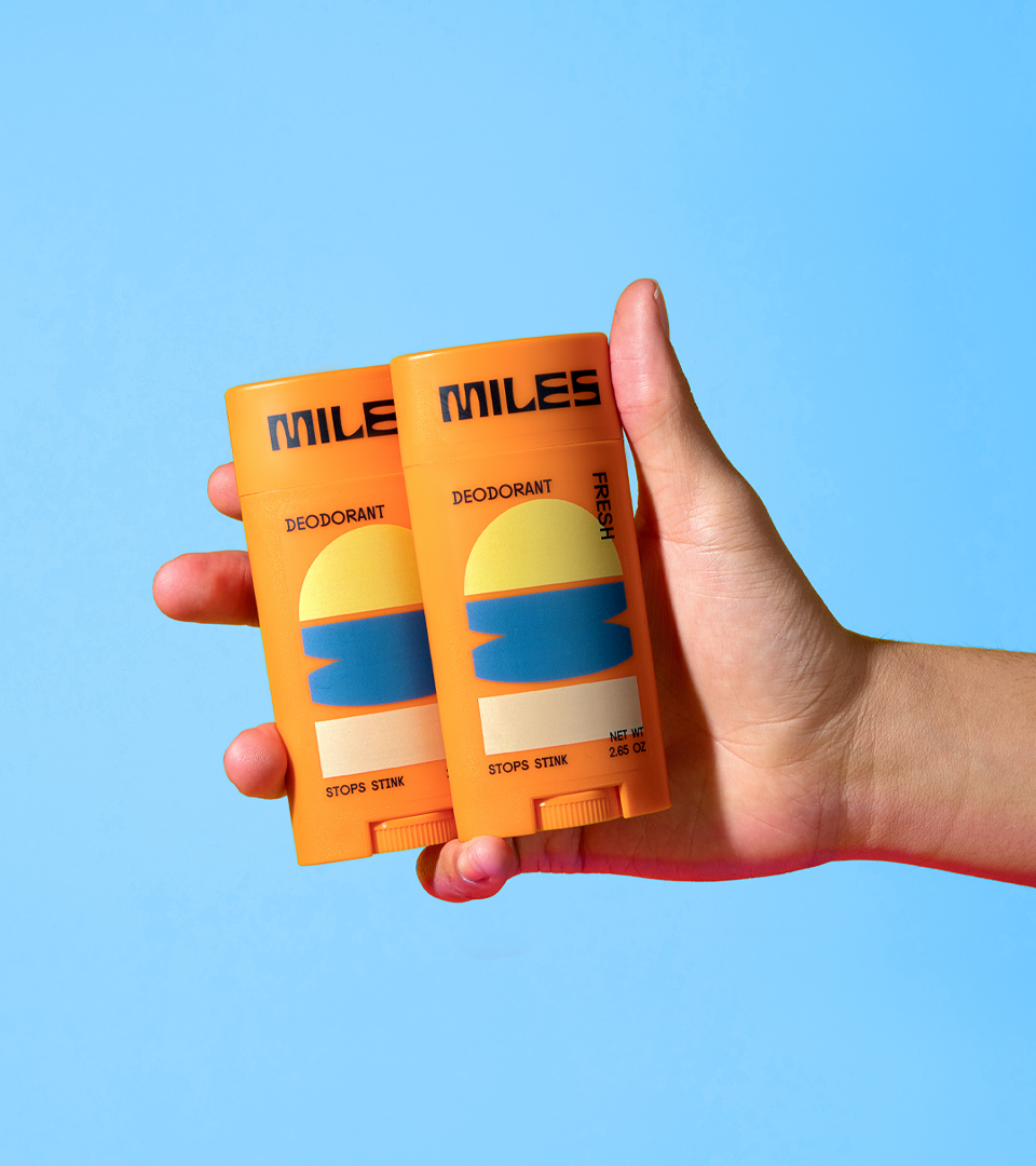 Hand holding two packs of Miles deodorant.