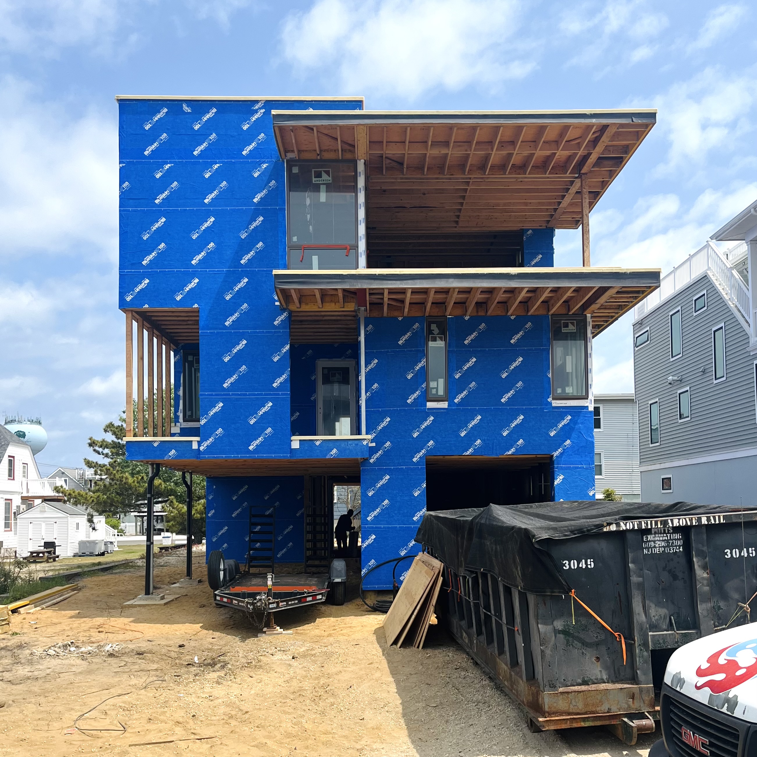 Exterior construction photo of The Gap House showing the vibrant blue Blueskin weather barrier fully installed and new windows in place, ready for exterior cladding.