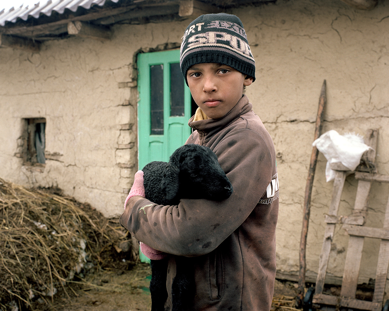 Paltinis, Romania. A child holds a lamb in front of his house. Paltinis, a small village in the Vaslui region, is mainly populated by Gypsies, entirely devoted to agriculture and livestock farming. In order to produce shale gas, Chevron wants to install its second Romanian fracking well here in Paltinis