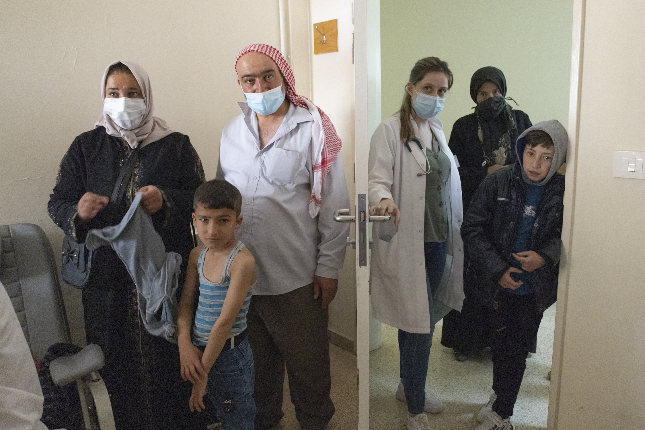 Rima Othman, a third-year medical student, leads a family into a consultation room for echocardiogram testing while another family waits for theirs.